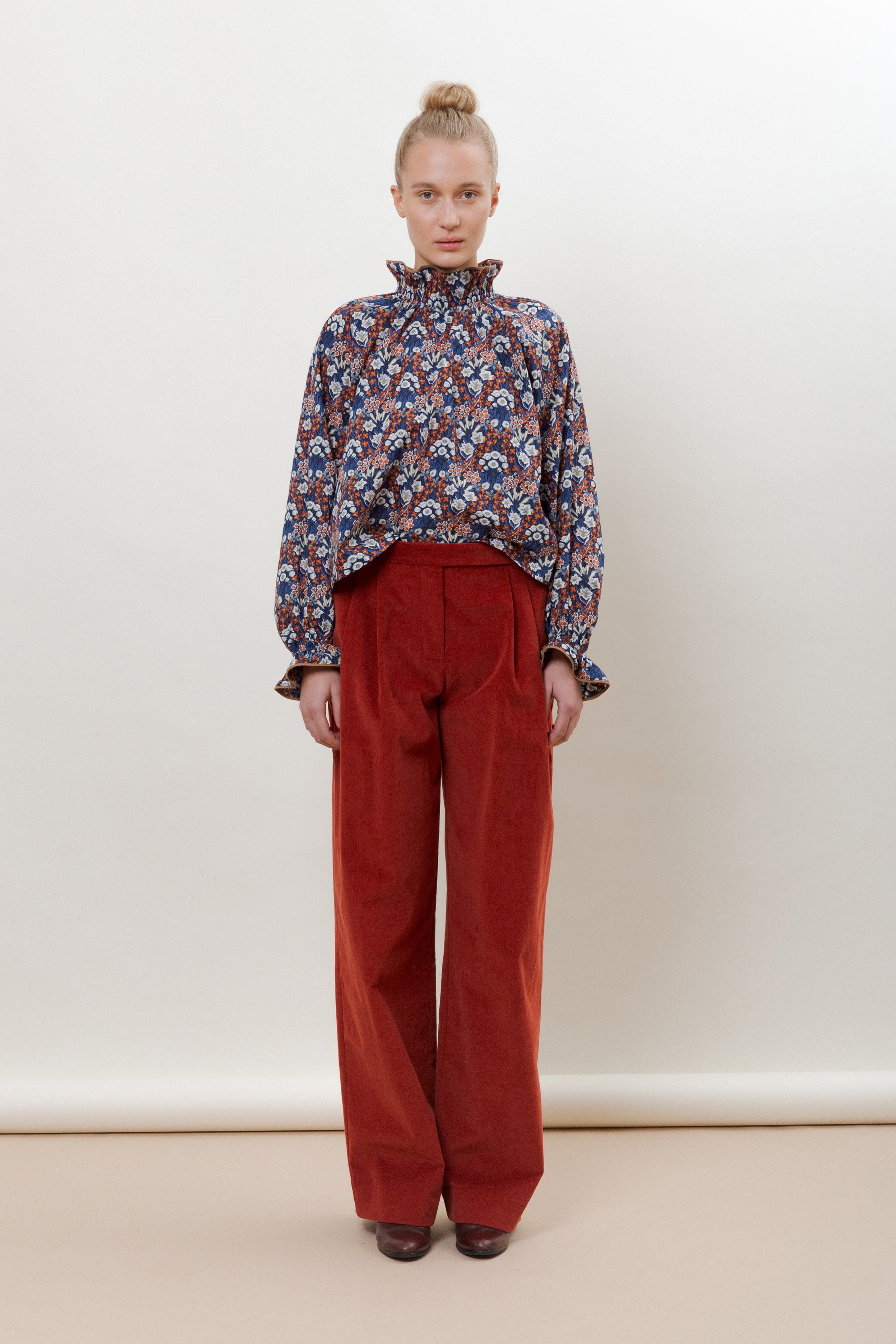 Woman in red pants and long sleeved blouse with red blue and white flower pattern