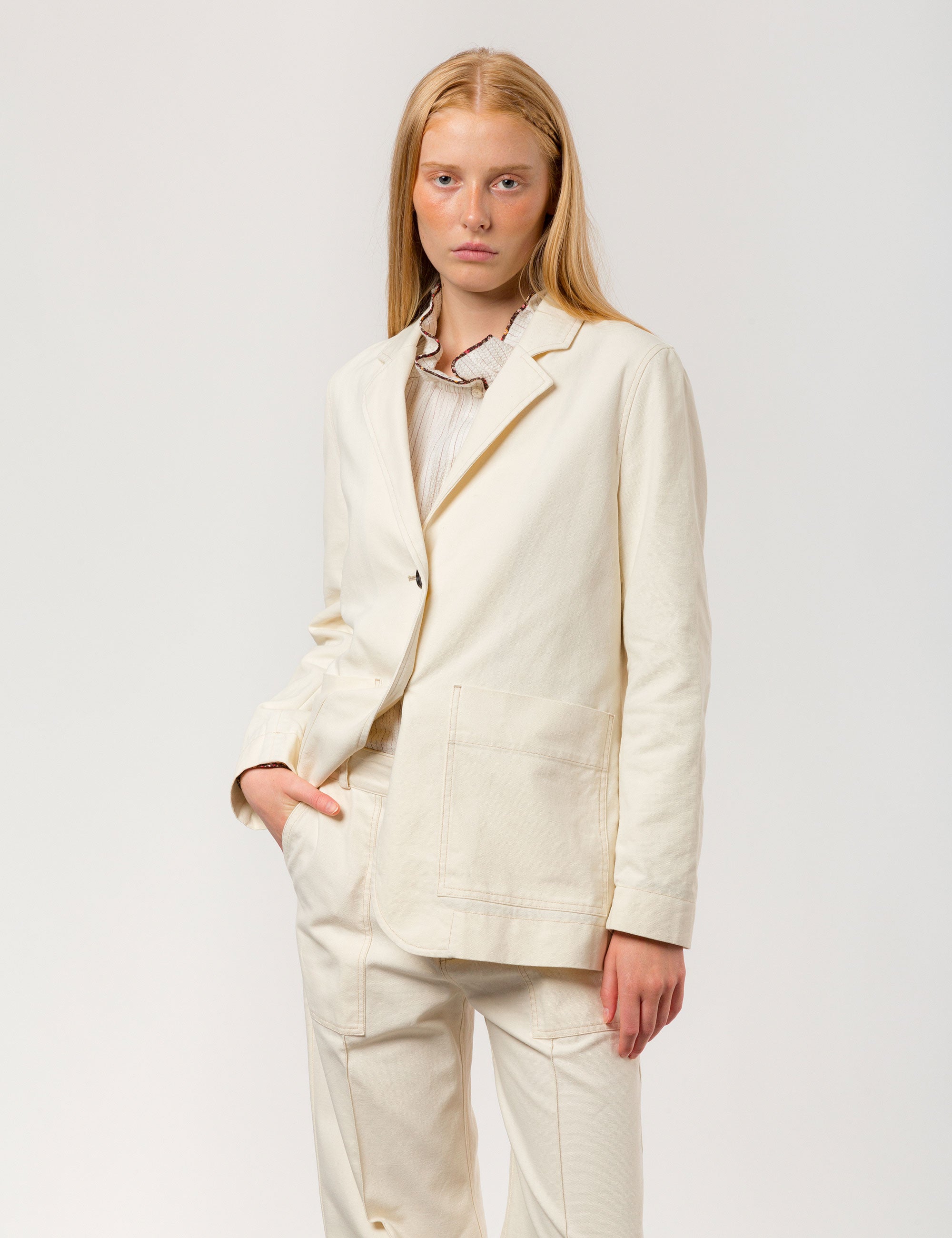 Woman in cream colored canvas jacket with large buttons and pockets and matching wide pants