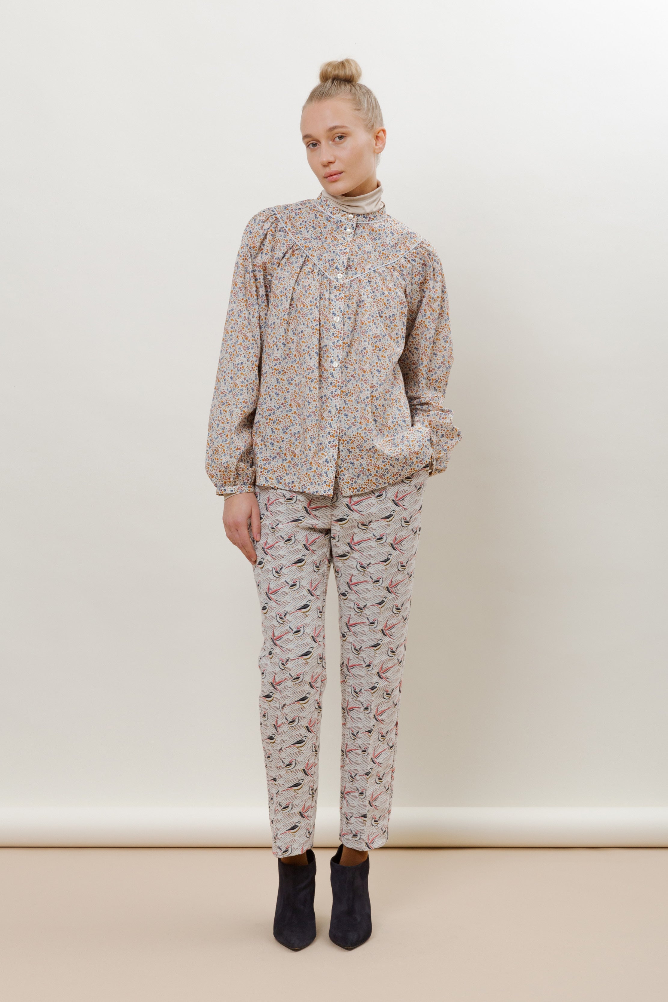 Woman in long sleeved blouse with flower pattern and trousers with pink bird pattern