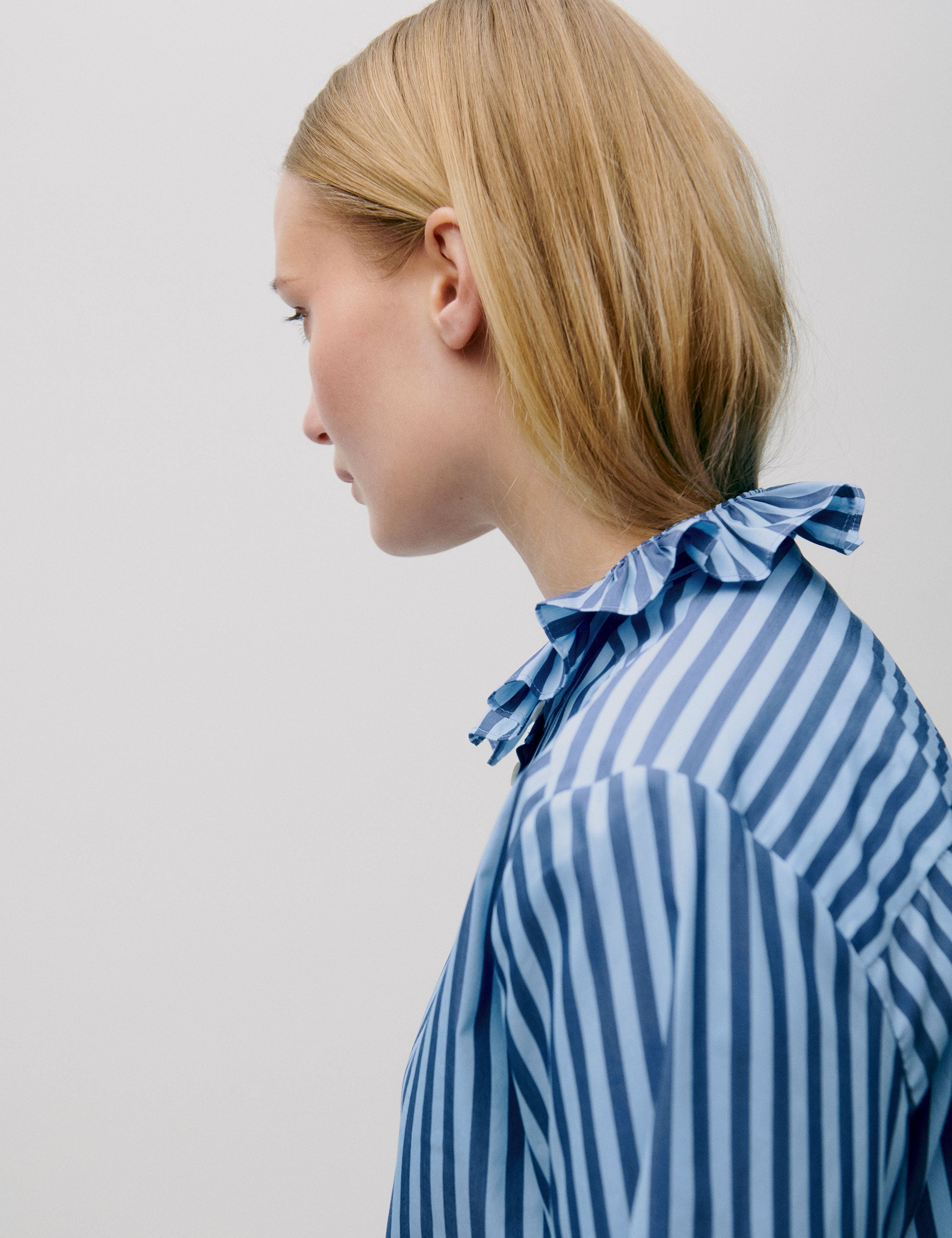 Side view of striped blouse showing ruffle detail at collar and back neckline