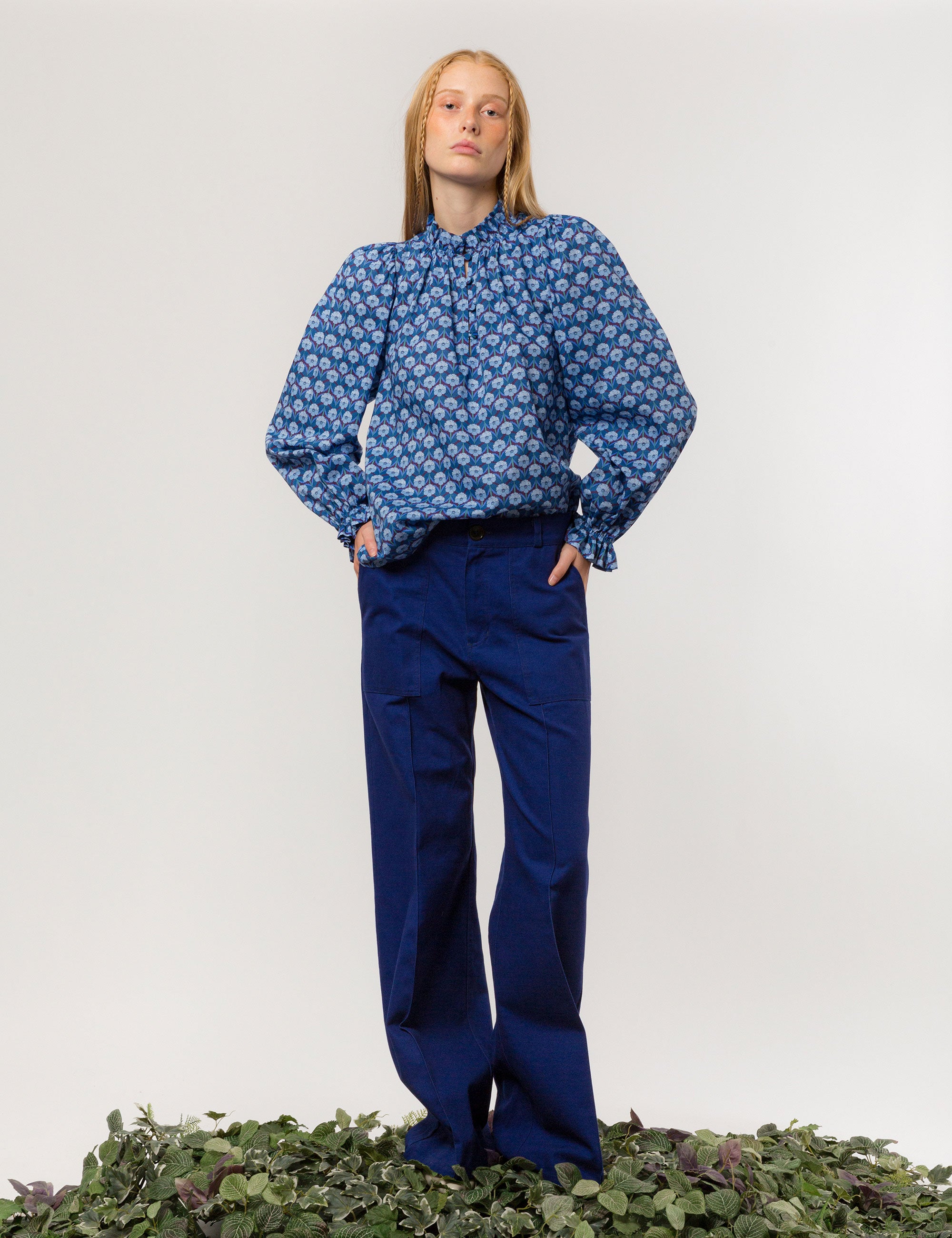 Woman in wide cut canvas pants in indigo blue color and long sleeved blue and white floral patterned shirt