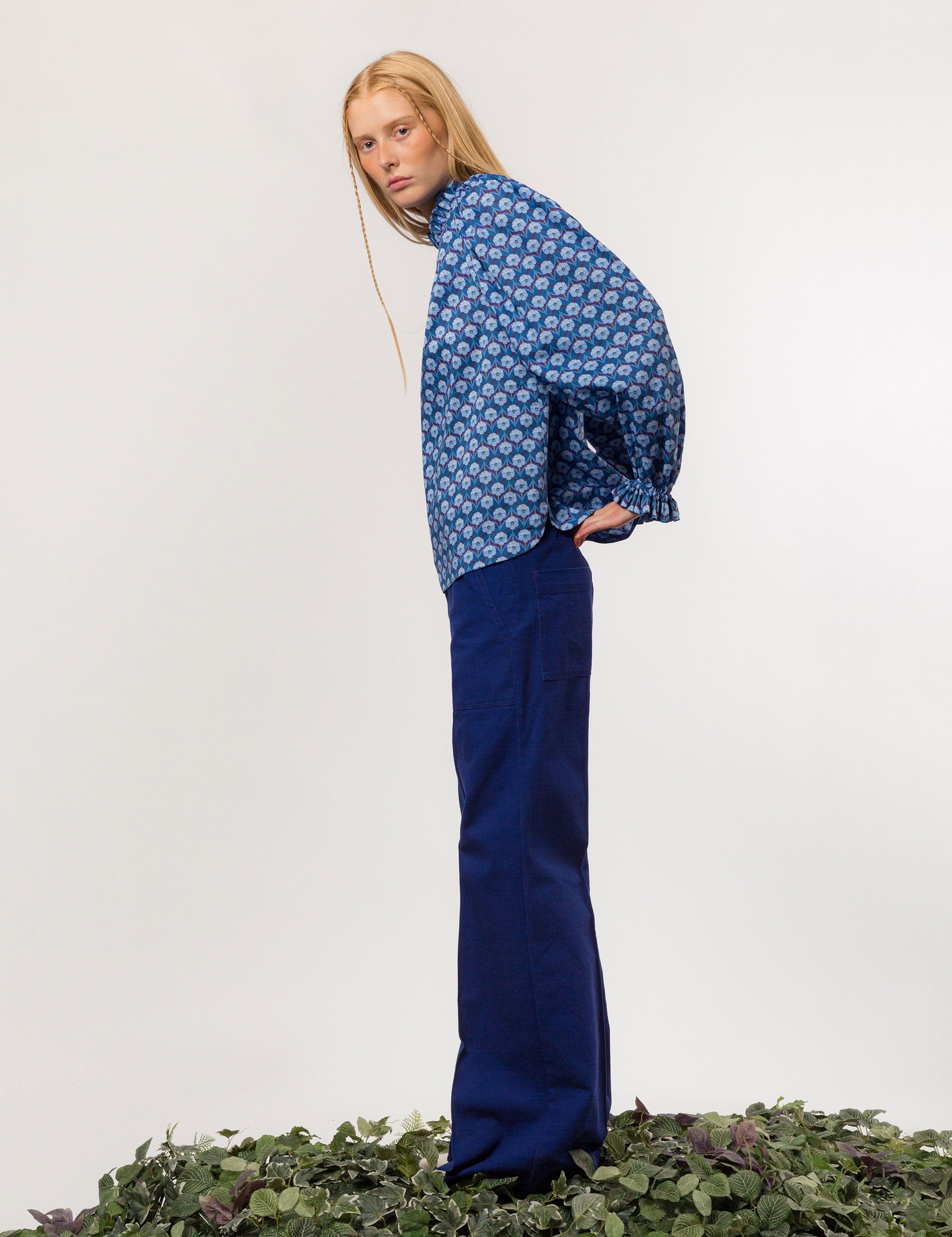 Woman in wide cut canvas pants in indigo blue color and long sleeved blue and white floral patterned shirt