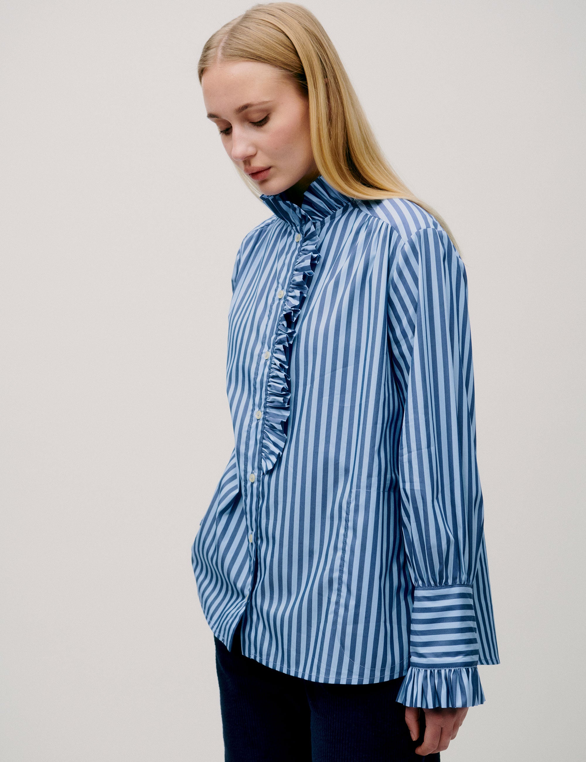 Side view of woman in blue striped blouse with gathered details
