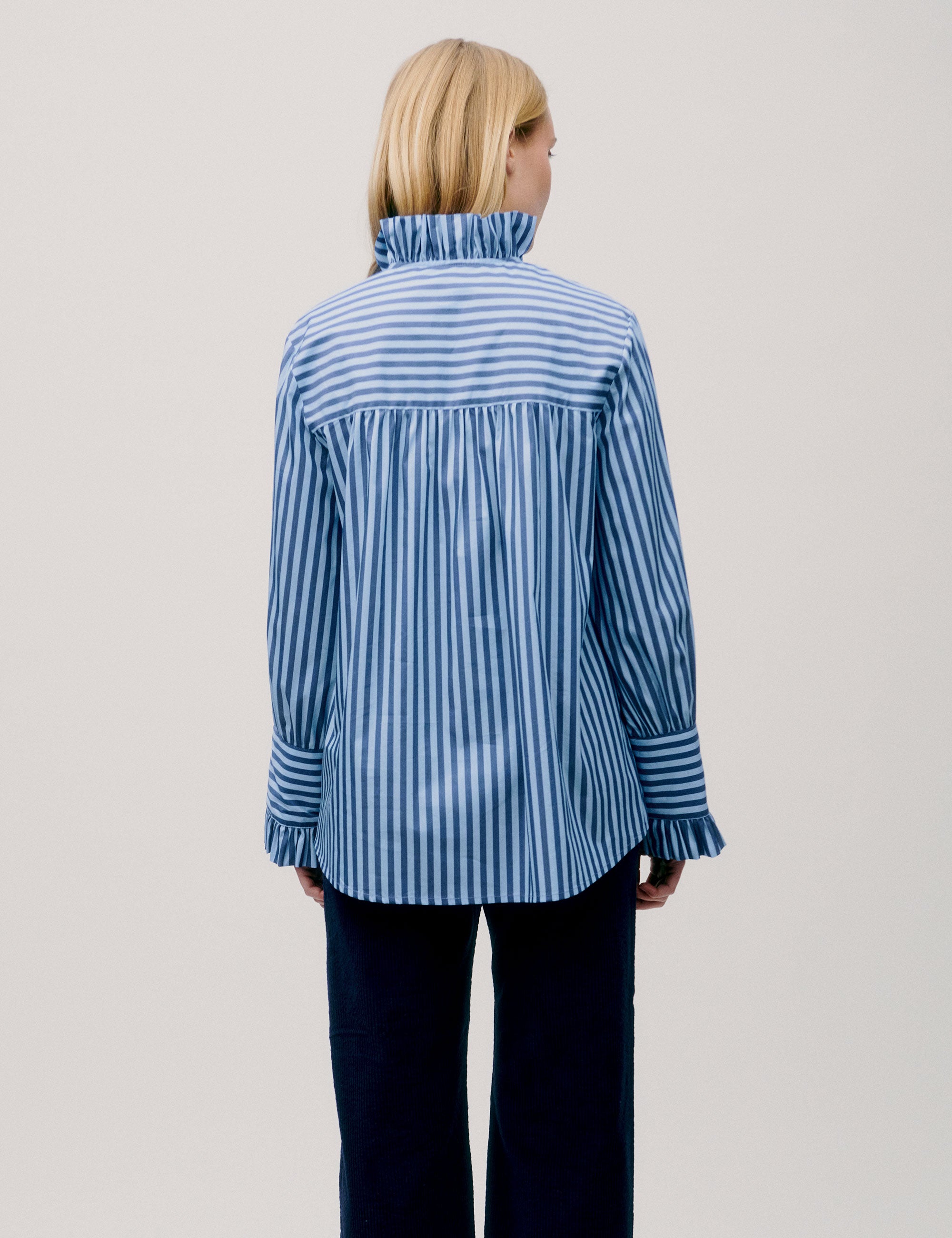 Back view of woman wearing loose-fit blue striped shirt