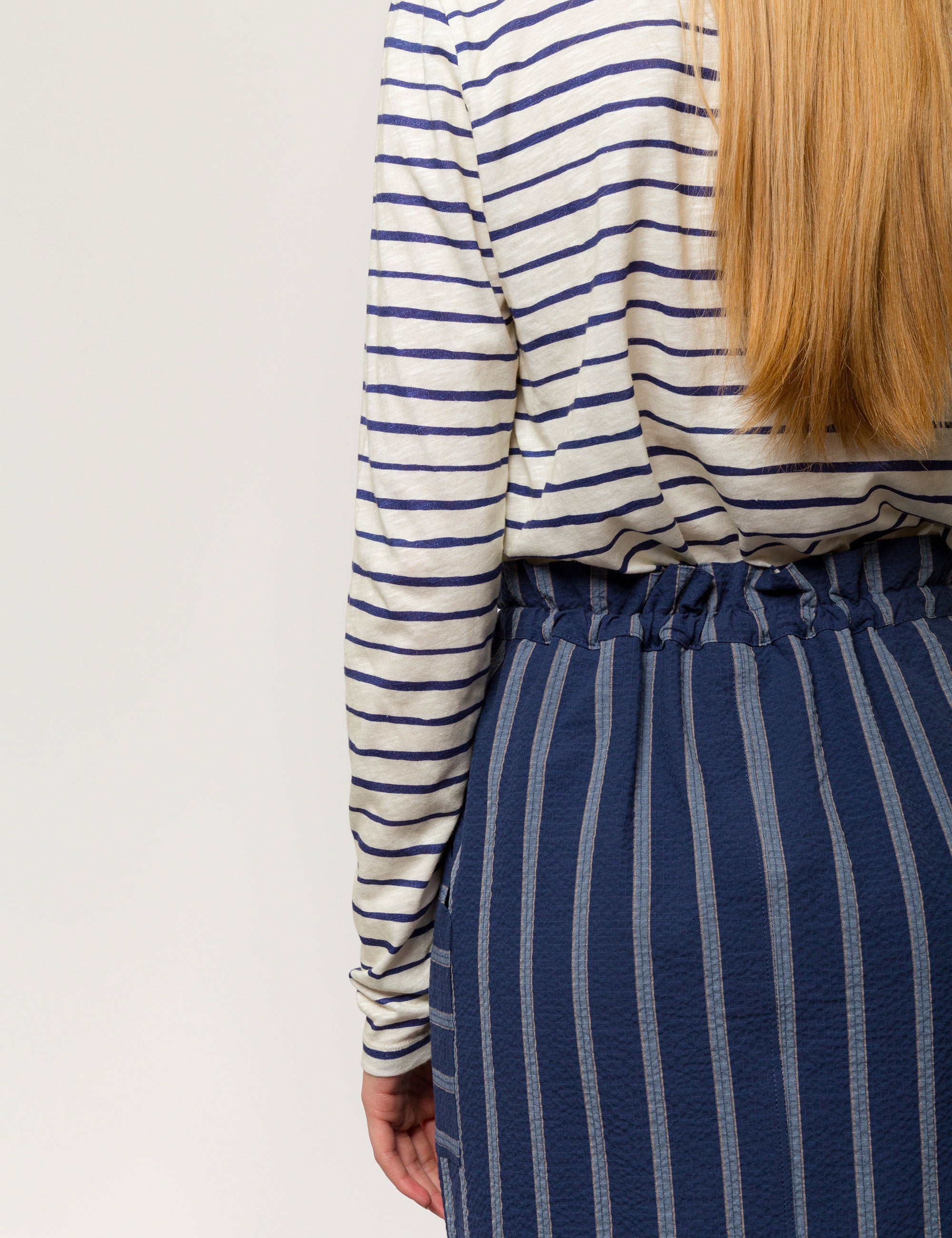 Woman in long sleeved white and blue striped cotton jersey t-shirt and blue and white striped skirt