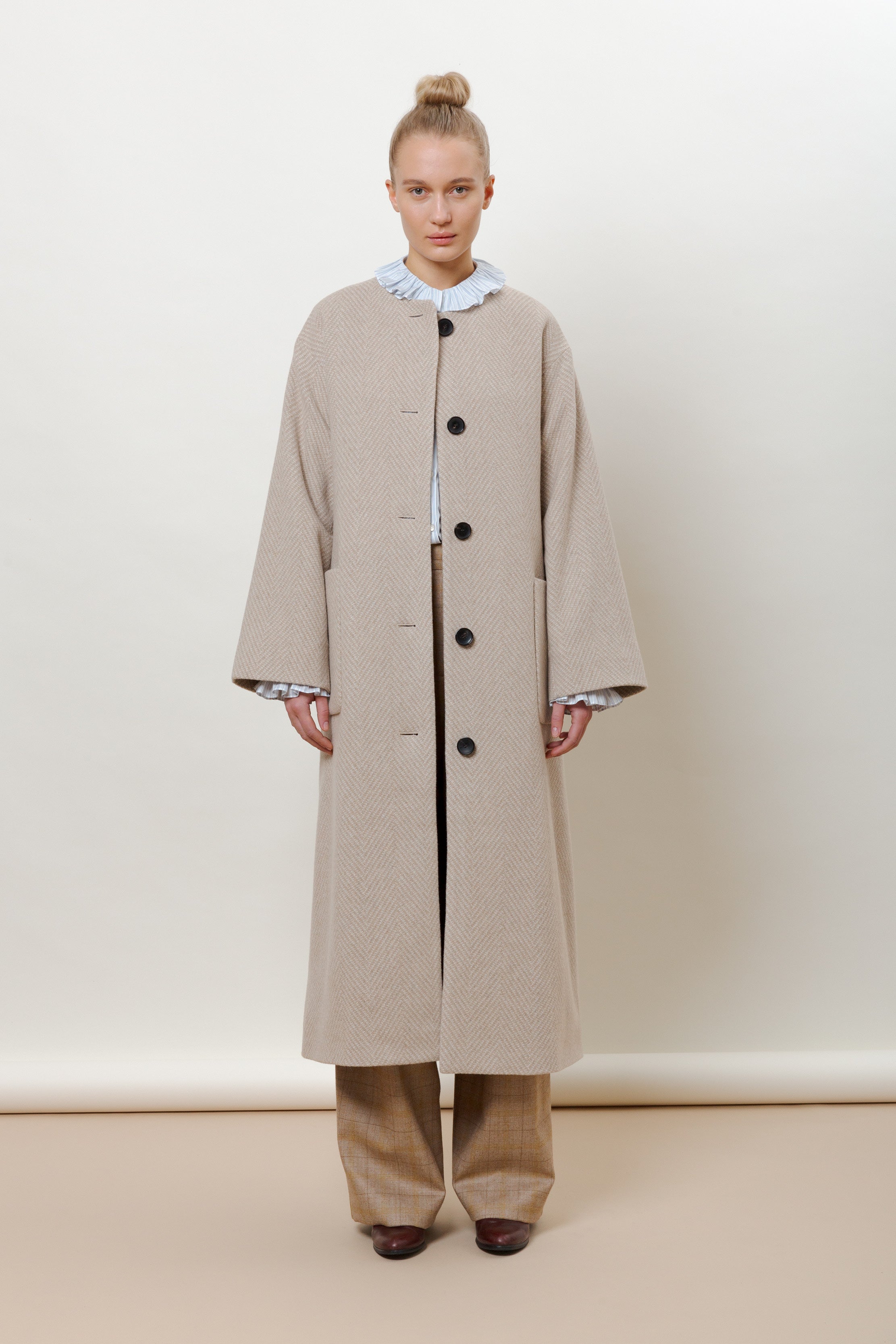 Woman in beige long herringbone wool coat with belt