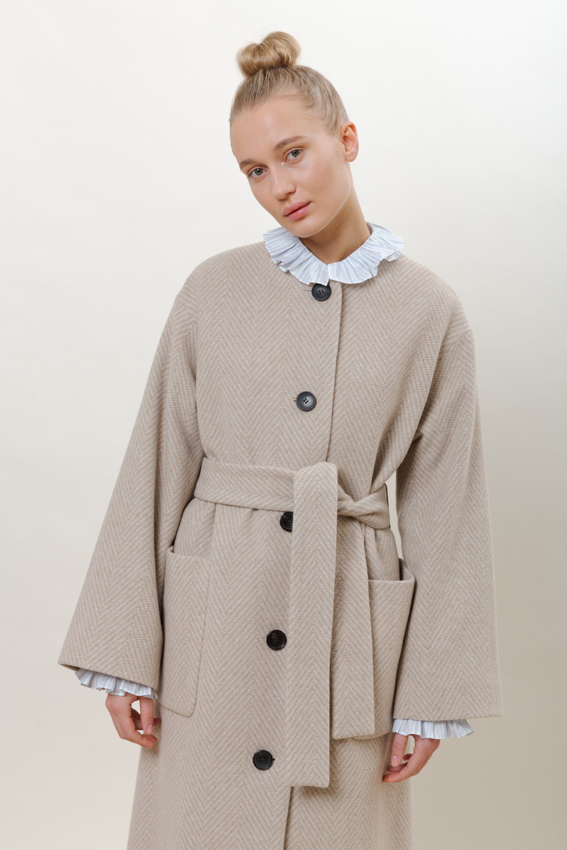 Woman in beige long herringbone wool coat with belt