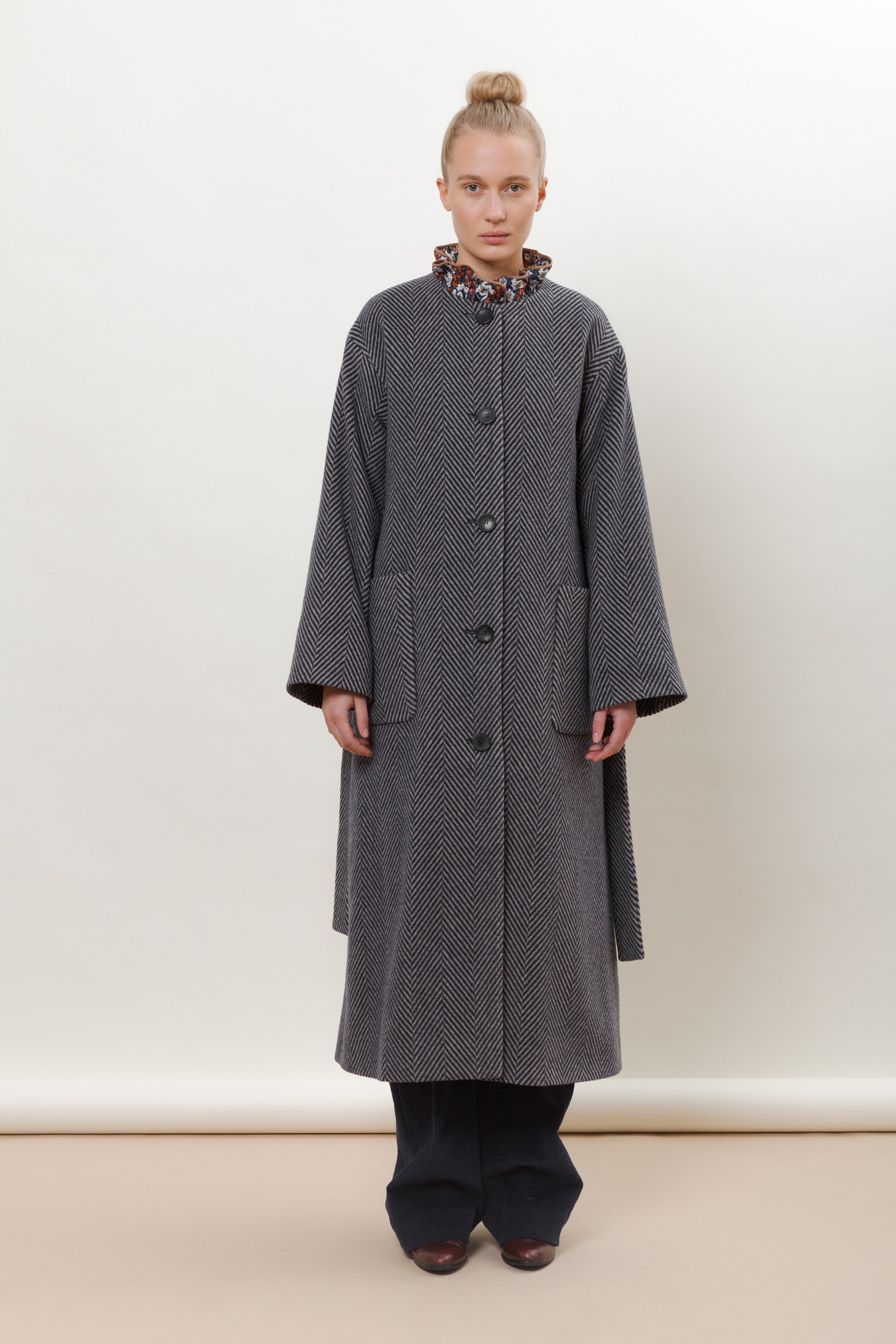 Woman in blue herringbone coat with belt and buttons