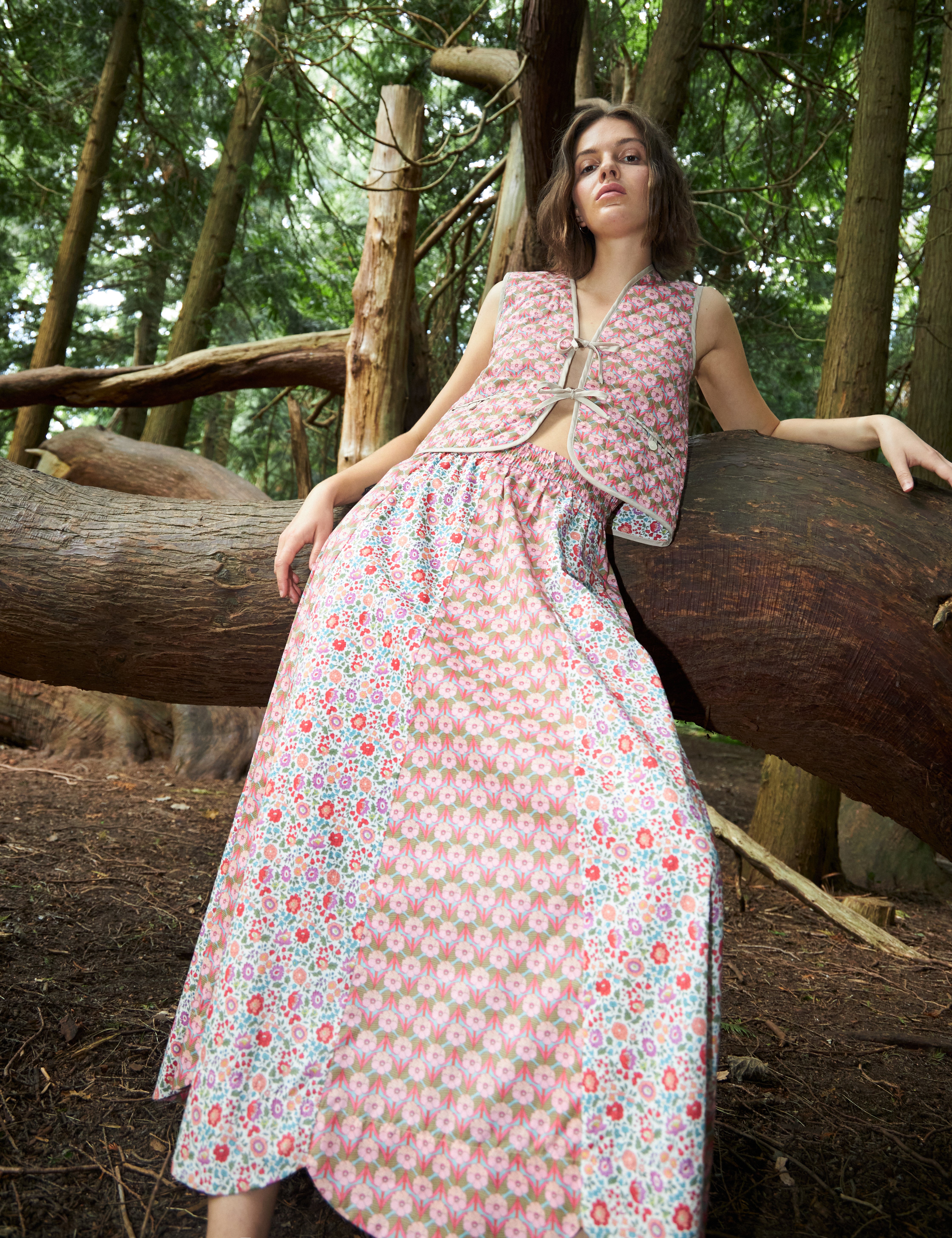 Woman in maxi skirt with two different floral prints in pink red and green and matching vest with pink floral pattern