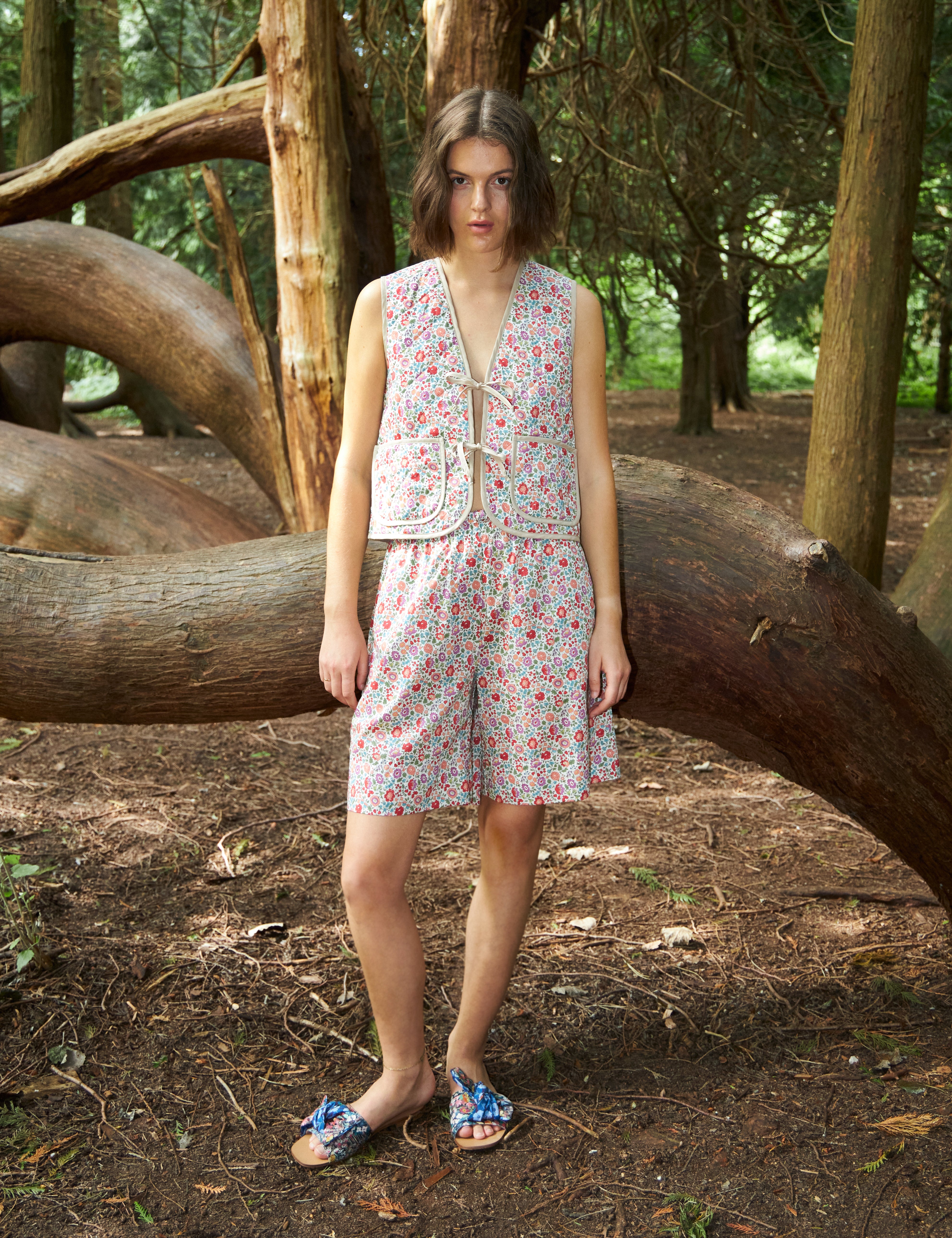 Woman in multi-colored floral print vest with pockets and matching shorts