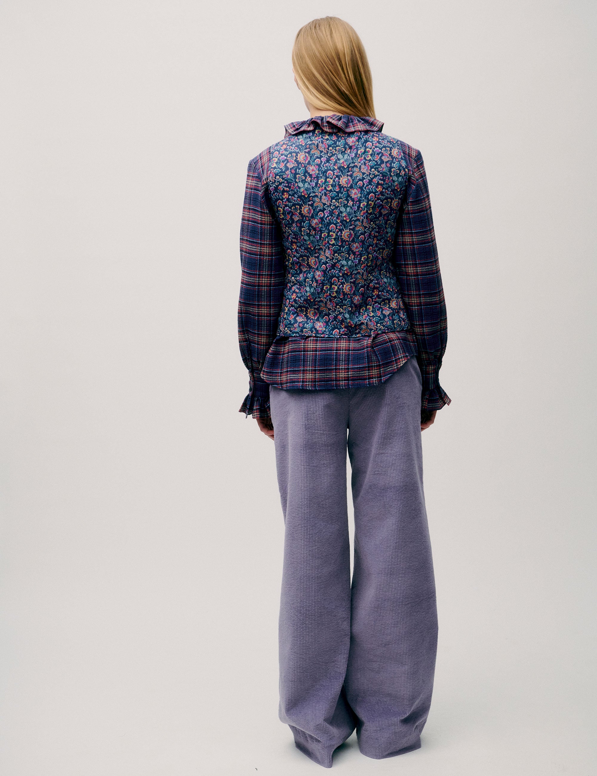 Back view of woman wearing wide-leg purple trousers and checked blouse