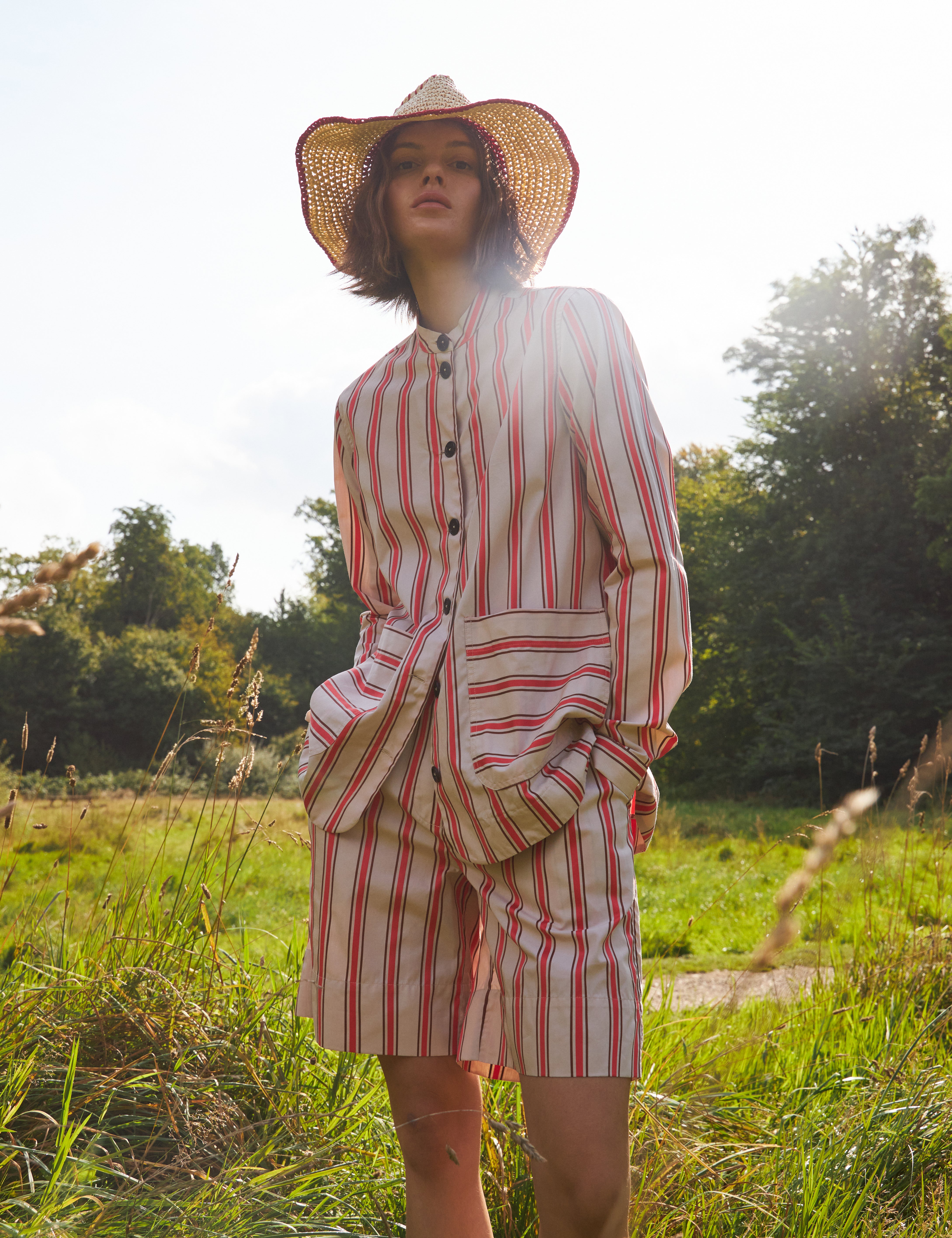 Woman in red and white striped shorts and red and white striped loose fit jacket with pockets and black buttons