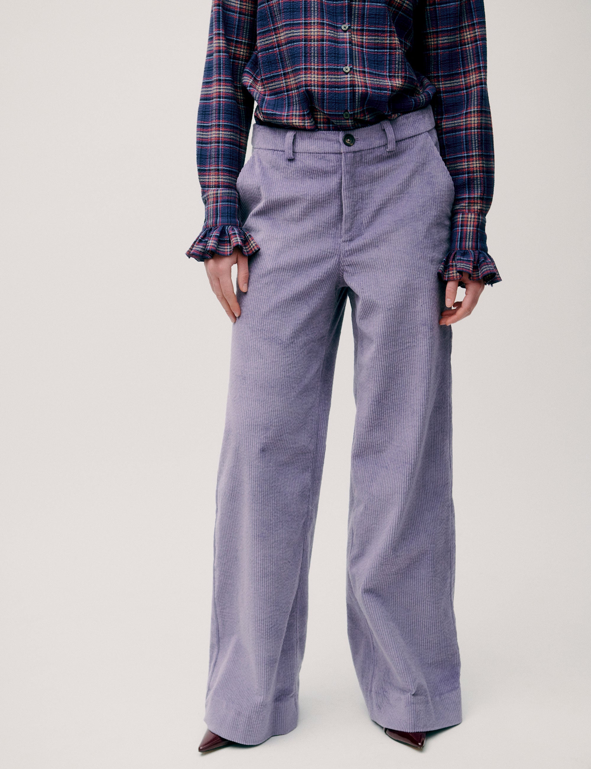 Close-up of purple corduroy trousers from the front, styled with plaid shirt