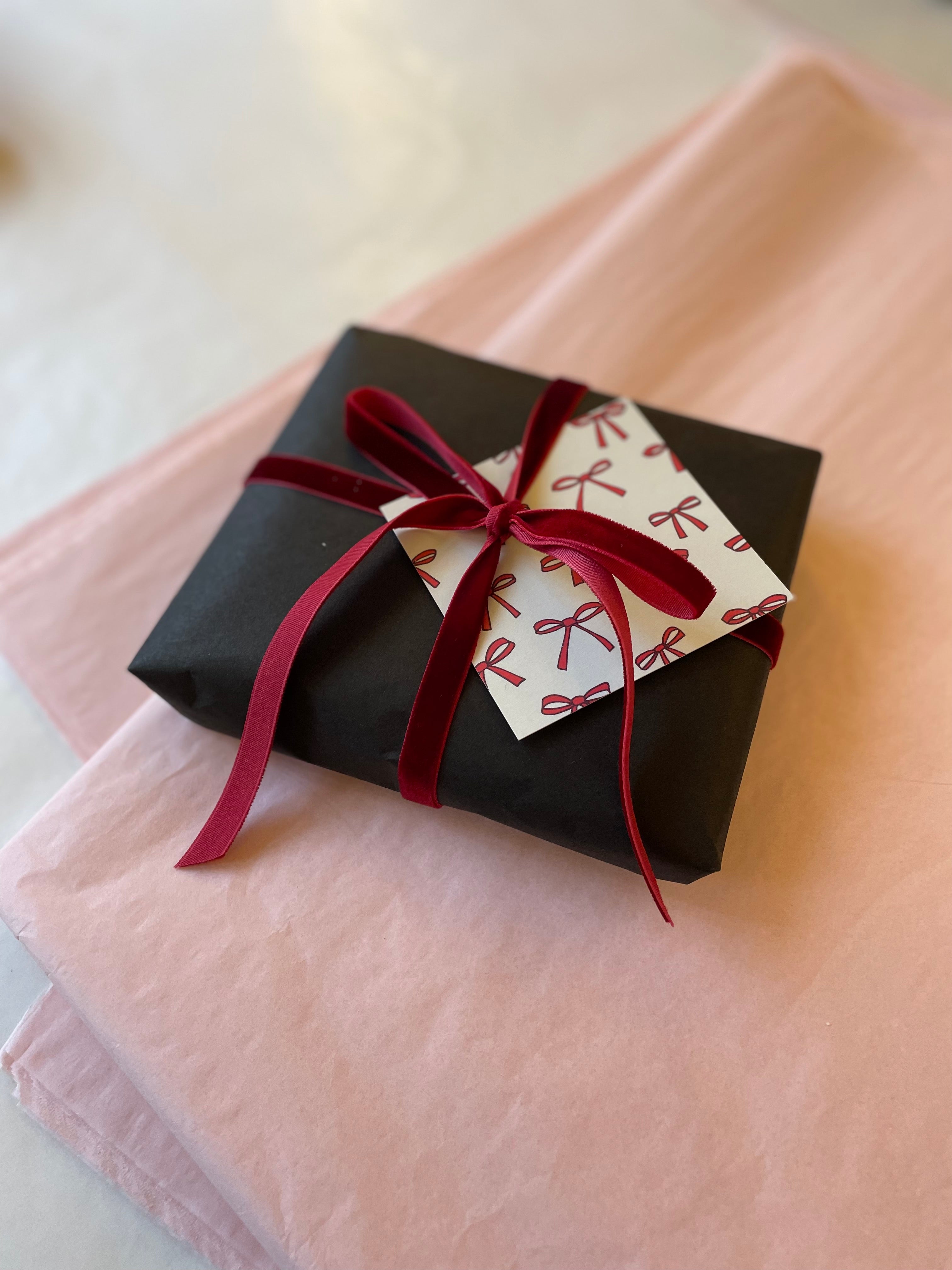 Gift with black wrapping, red ribbon and greeting card with red bows