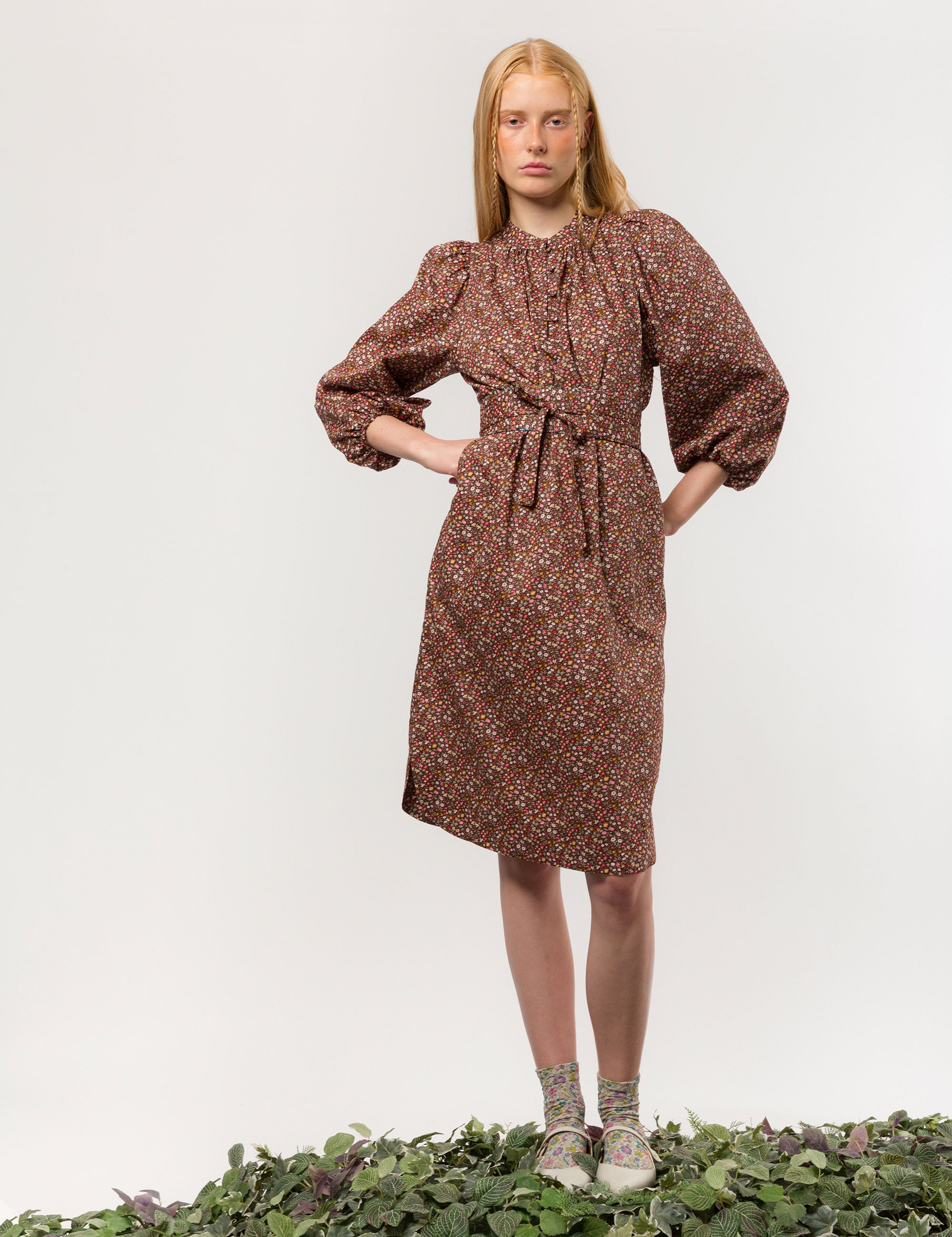 Woman in brown floral print midi dress in liberty cotton with long puff sleeves and matching belt