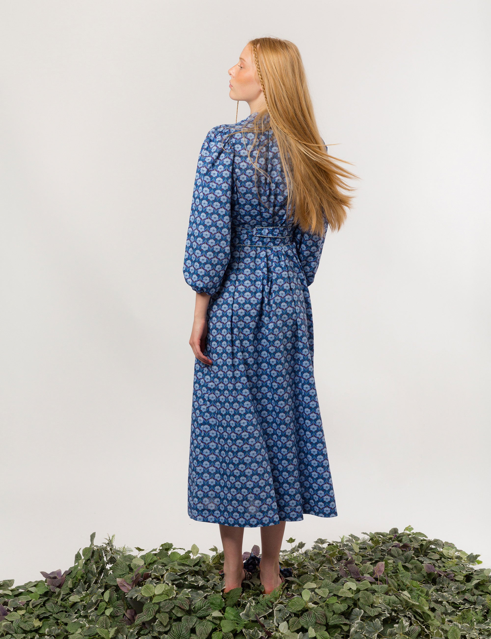 Woman in danish designed blue floral print maxi dress in premium Liberty cotton with long puffed sleeves and matching belt