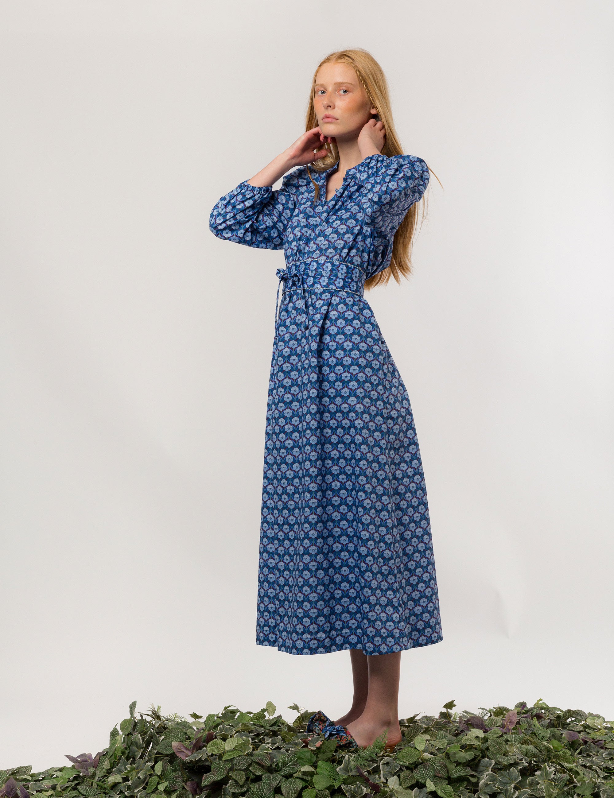 Woman in danish designed blue floral print maxi dress in premium Liberty cotton with long puffed sleeves and matching belt