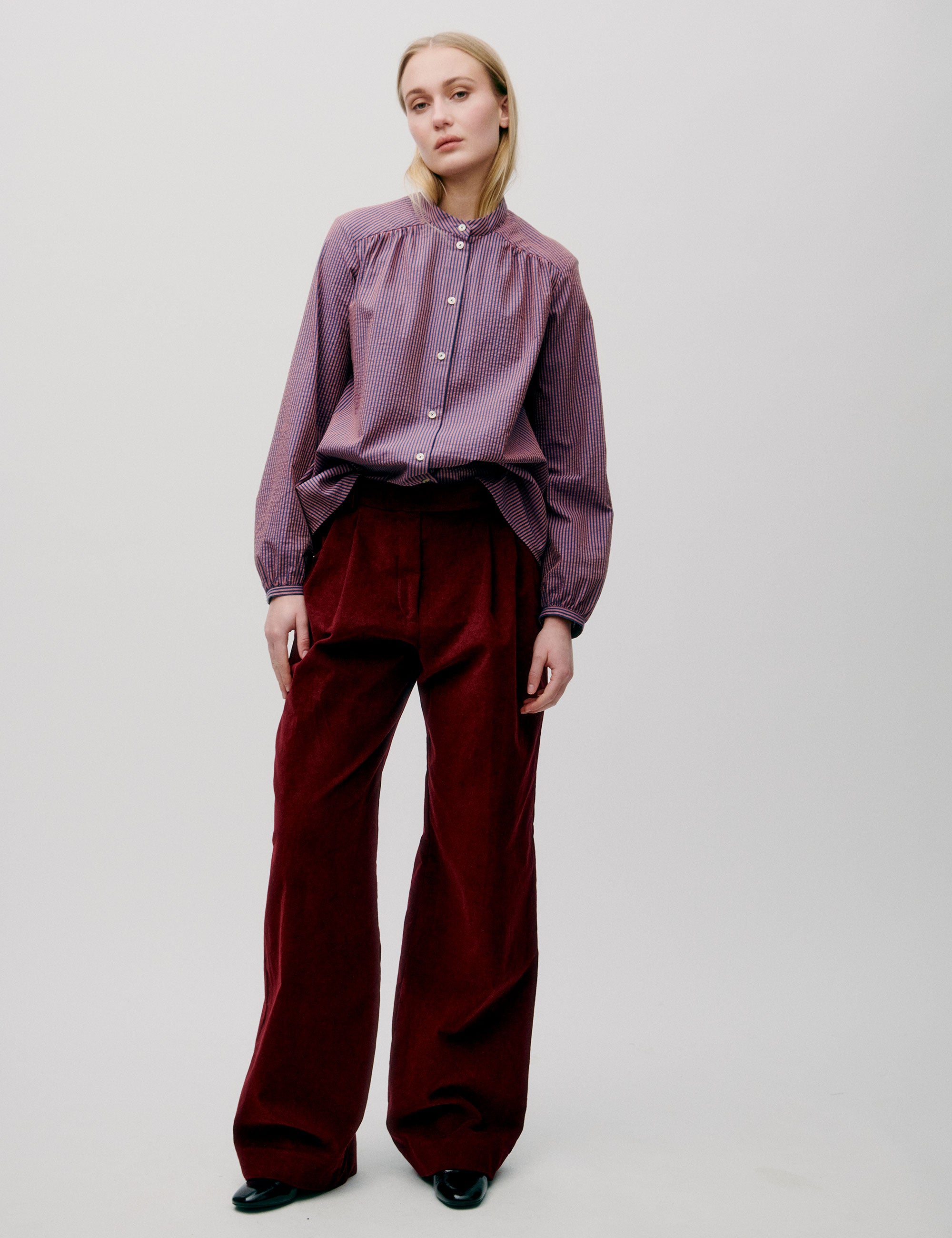 Woman in long sleeved pink striped shirt and red trousers