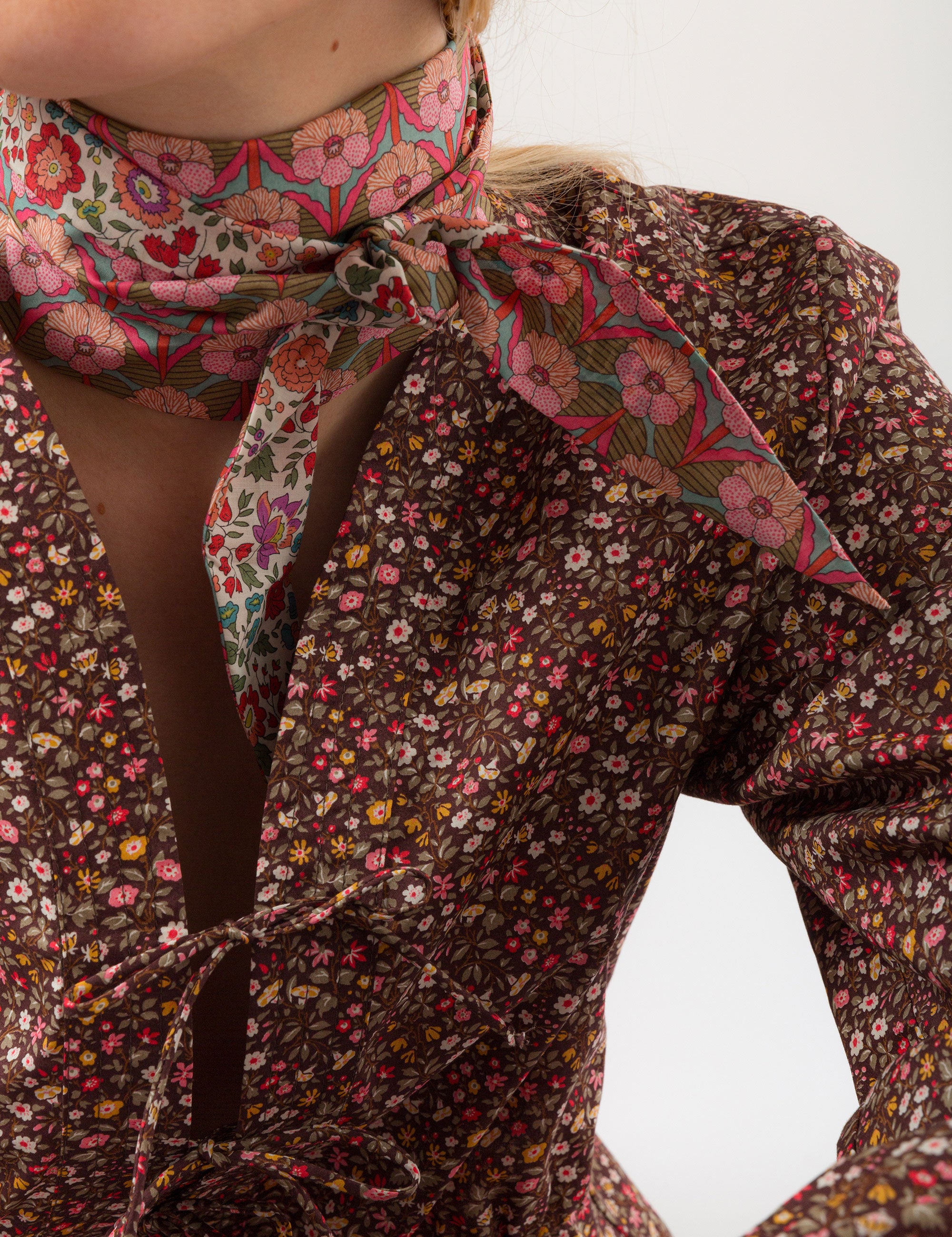 Woman in long-sleeved v-neck shirt in liberty cotton brown and red small floral print and pink floral patterned bandana around neck