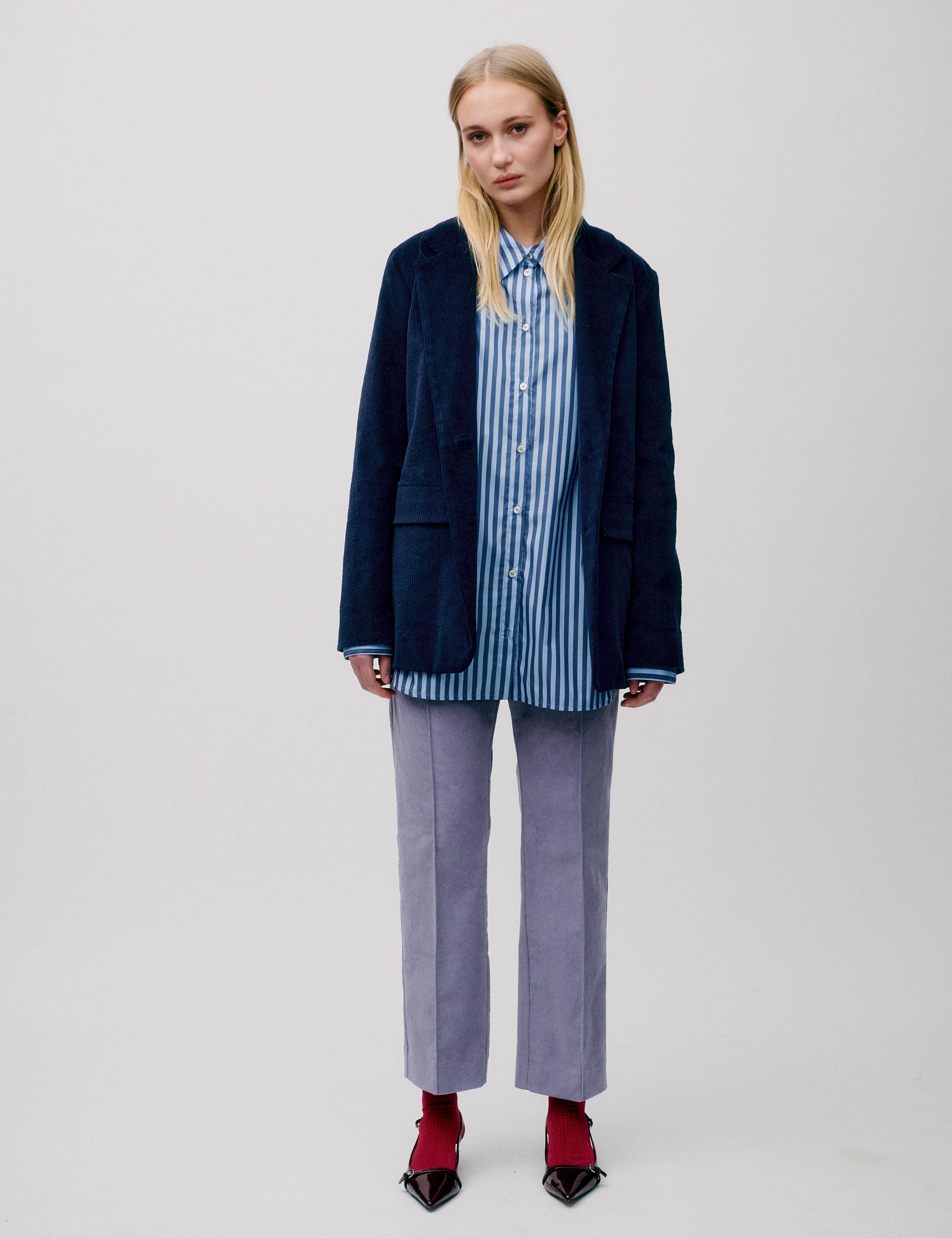Women in straight blue striped cotton shirt, dark blue corduroy jacket and lavender colored pants