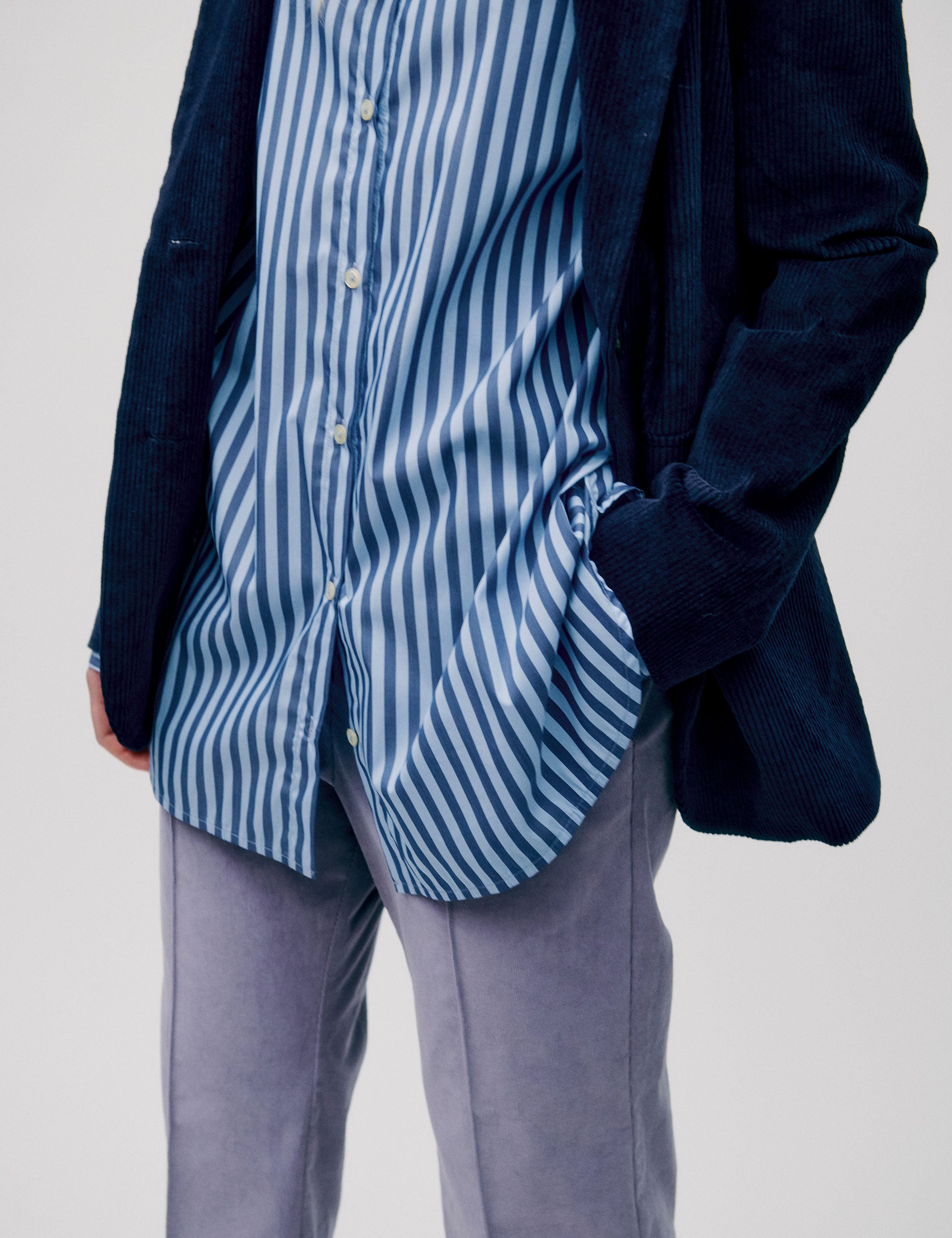 Women in straight blue striped cotton shirt, dark blue corduroy jacket and lavender colored pants