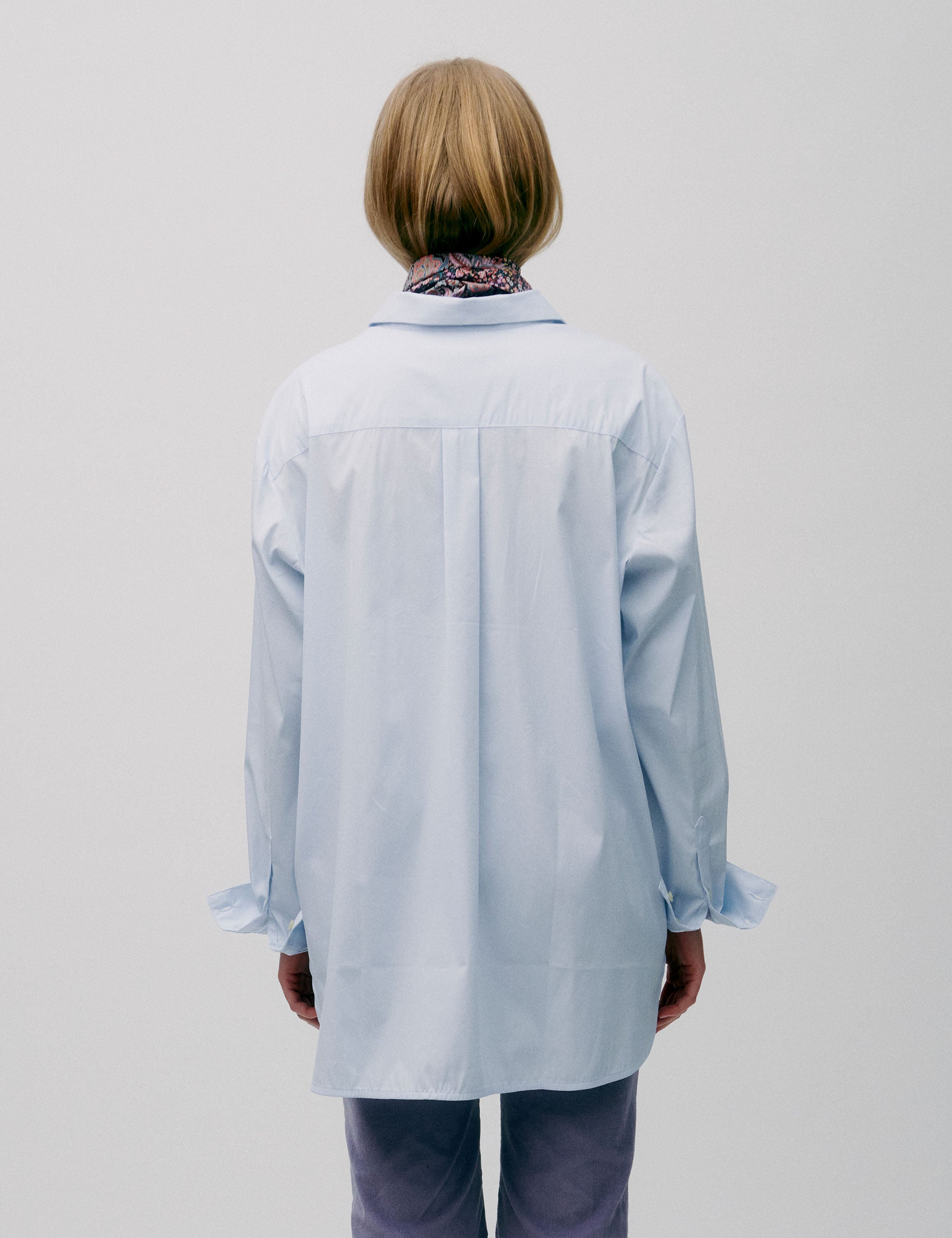 Woman in light blue straight cotton shirt with long sleeves and lavender colored corduroy pants
