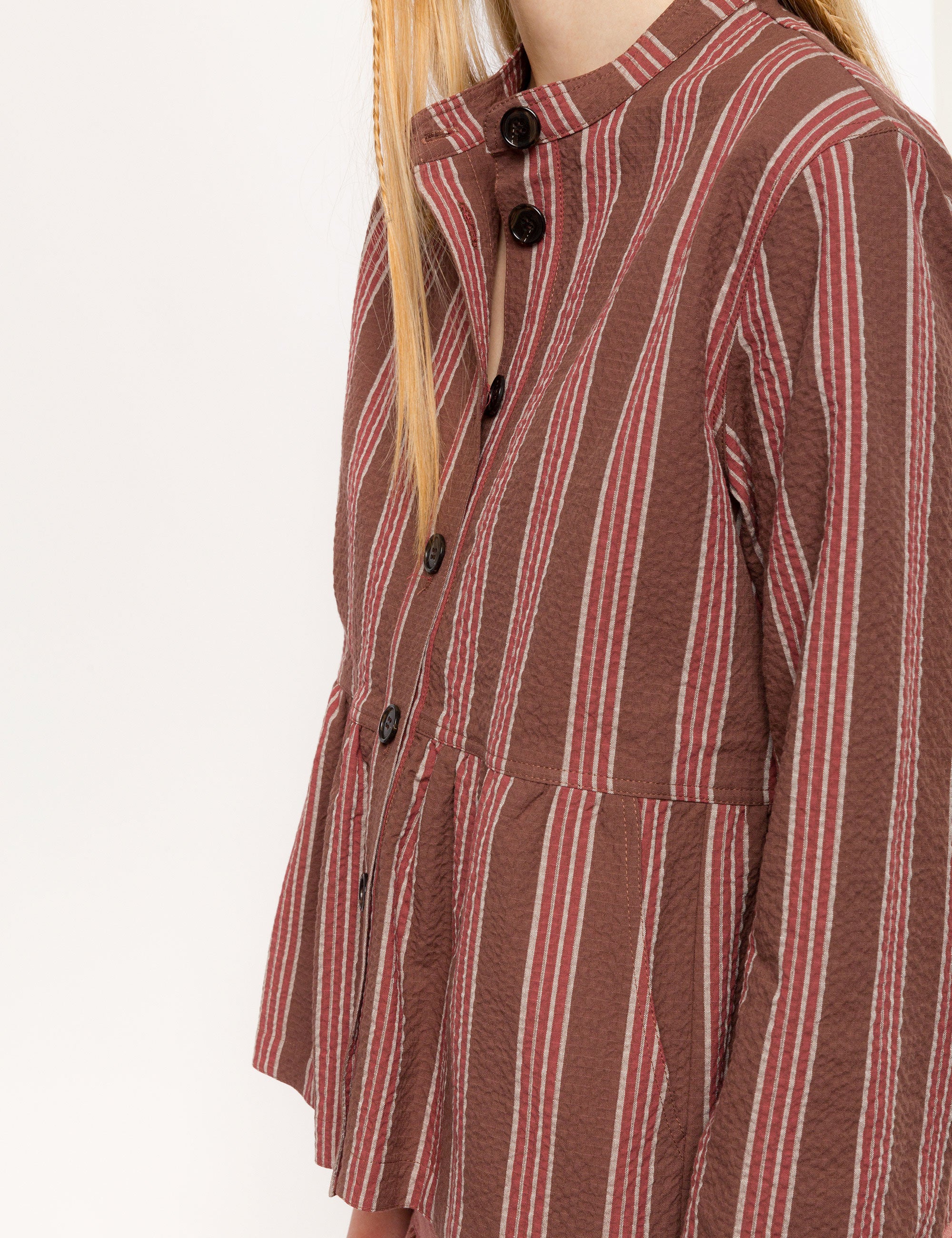 Woman in brown, white and red striped long sleeved cotton jacket with buttons and round neck