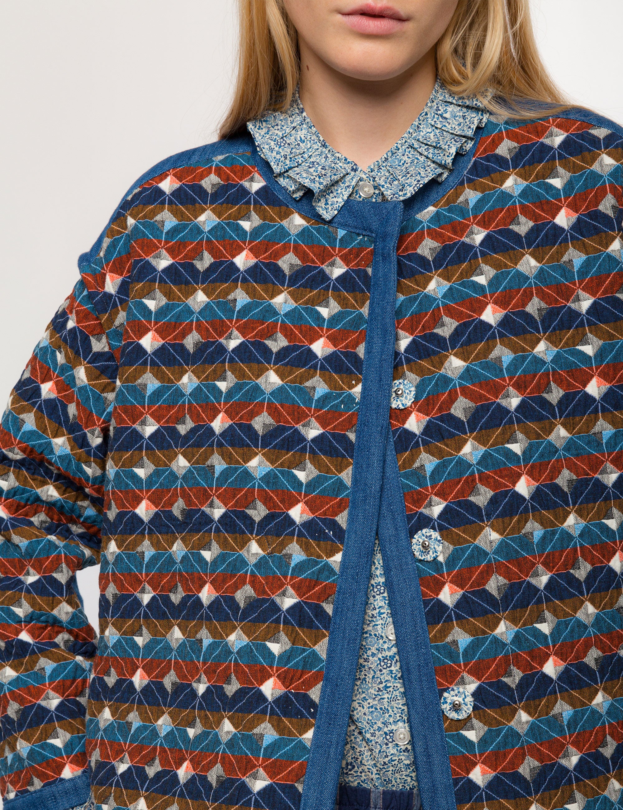 Check print multi-colored women's quilt jacket with long sleeves, buttons and blue pipings and blue floral patterned shirt with frilled cuffs