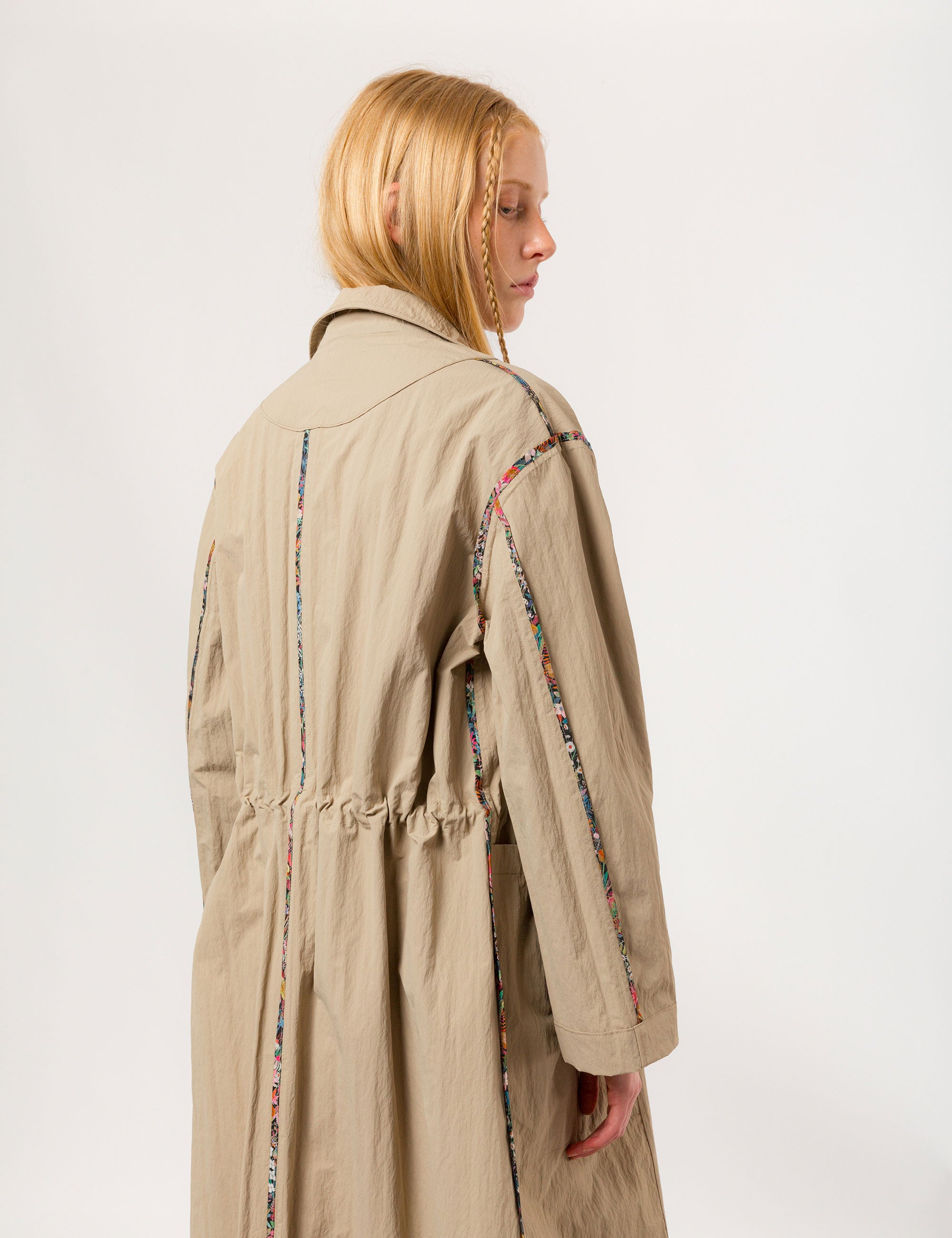 Women in long khaki coat with buttons, large pockets and floral print pipings