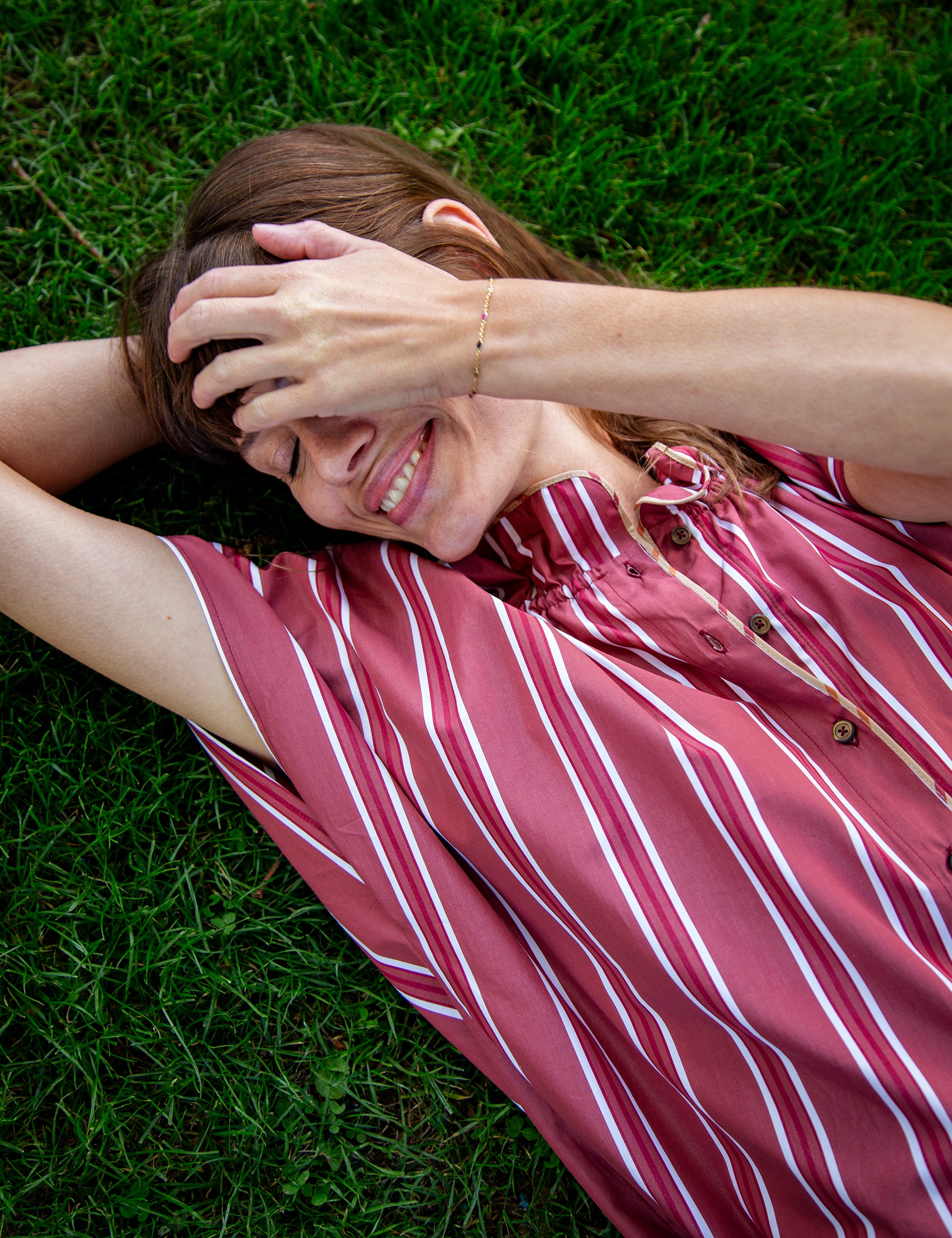 Woman lying on grass wearing a red and white striped shirt