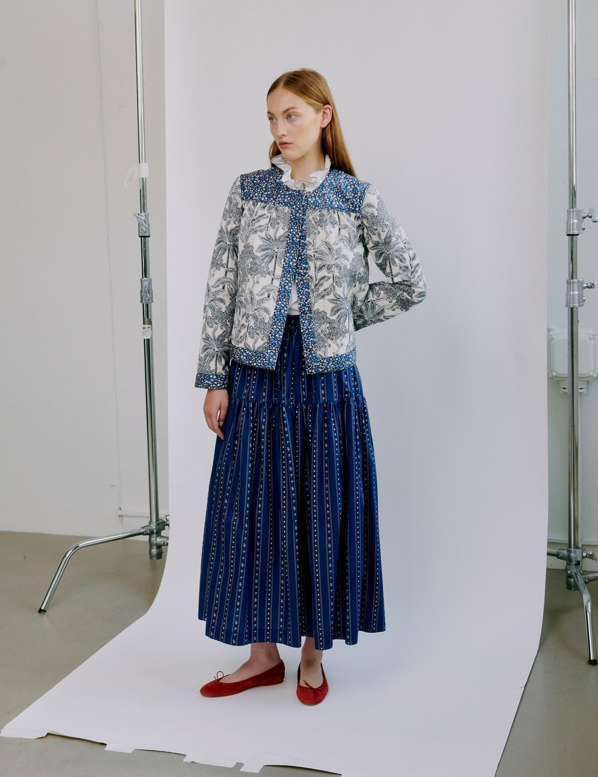 Woman wearing a blue patterned jacket and blue skirt in a photo studio