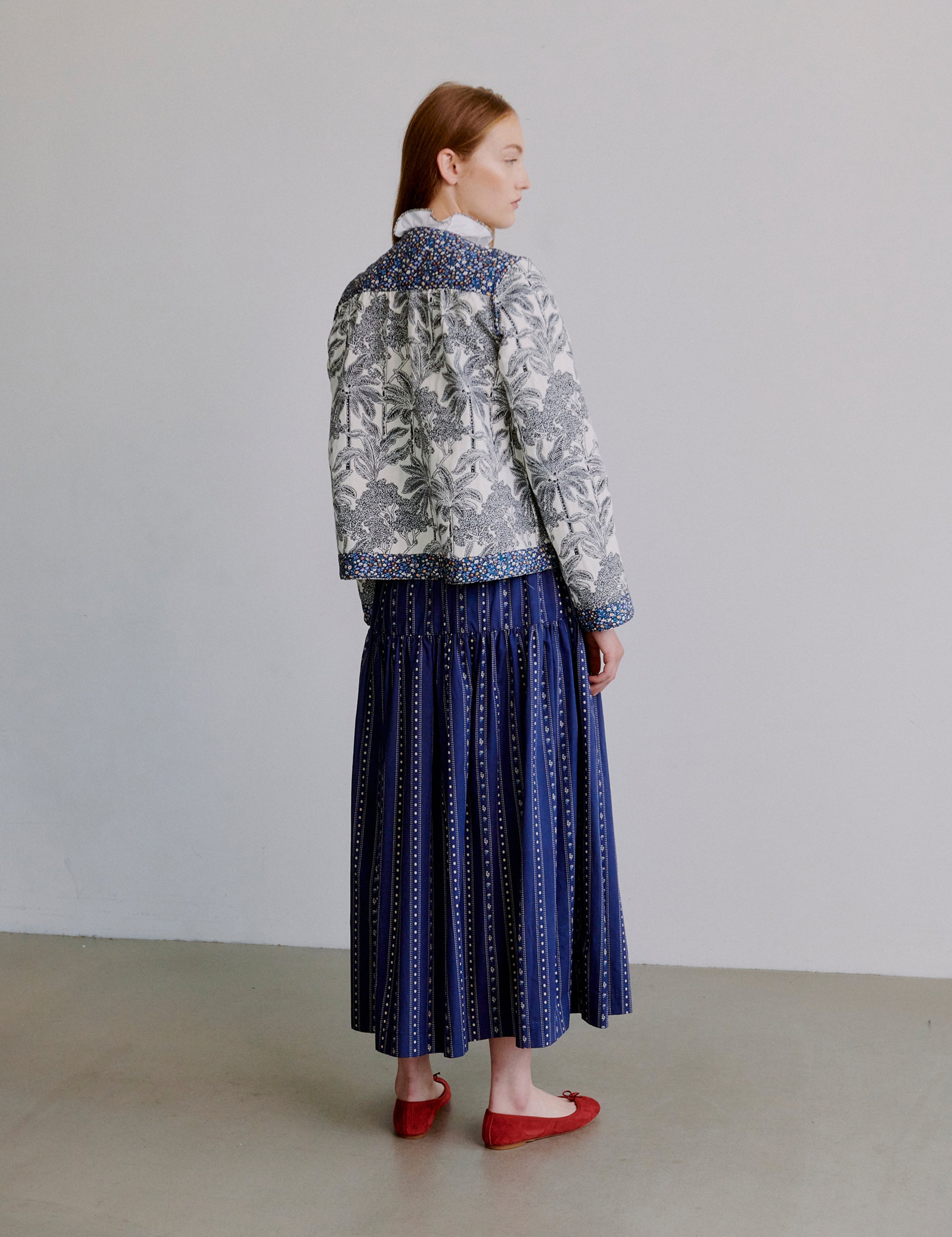 Woman wearing a blue patterned jacket and blue skirt