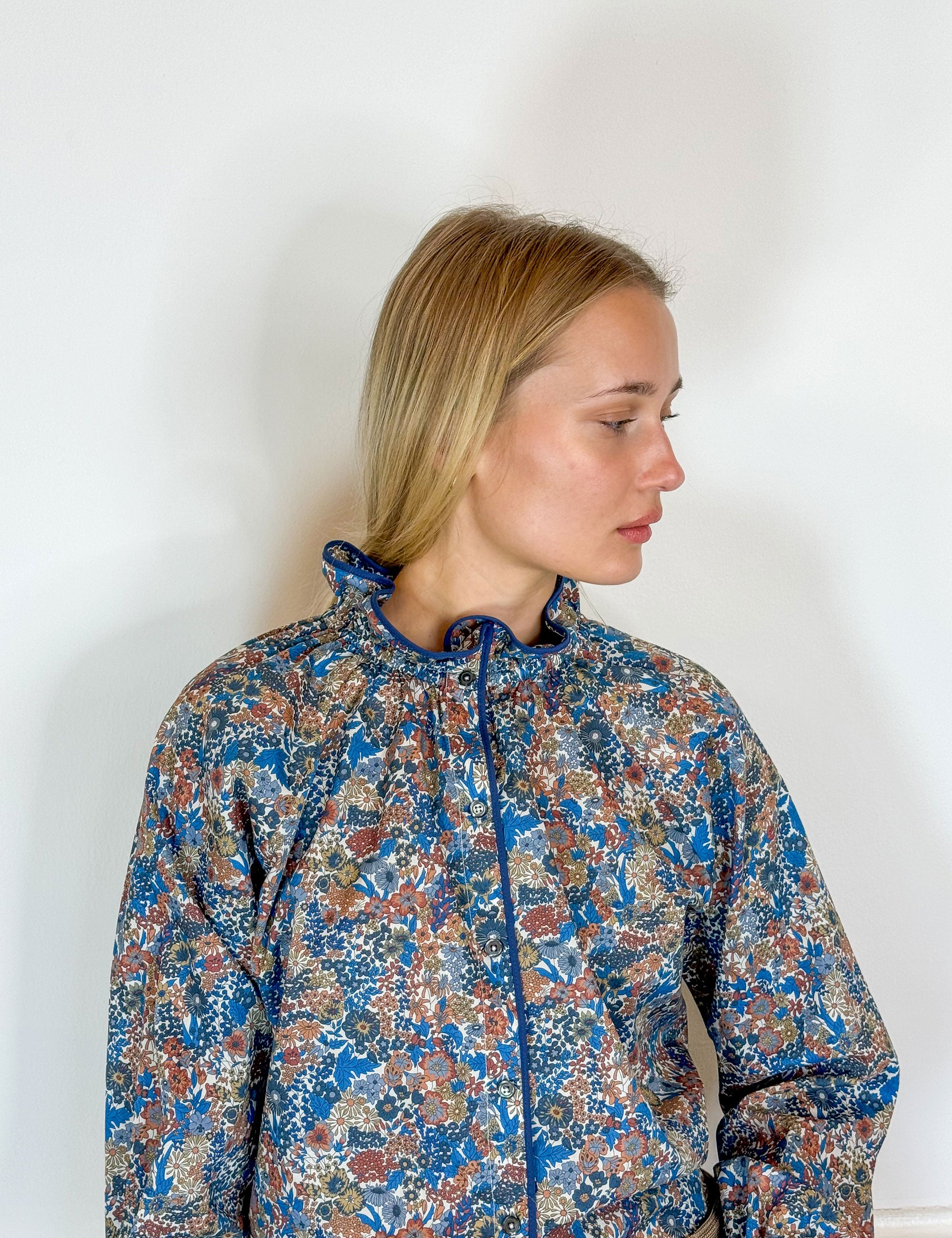 Woman in multi-colored floral print shirt with long sleeves and frilled collar