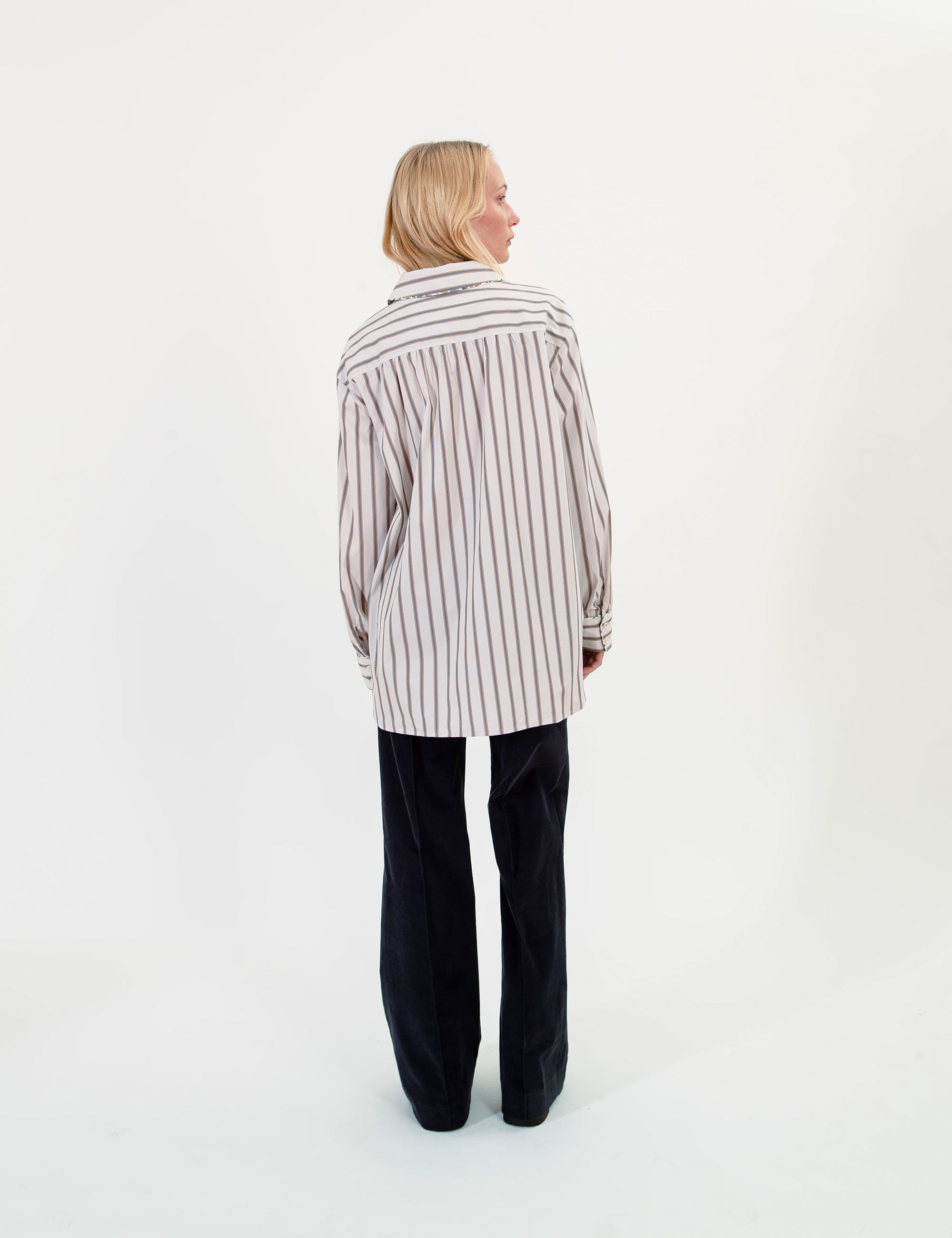 Woman wearing a striped shirt and black pants on a white background