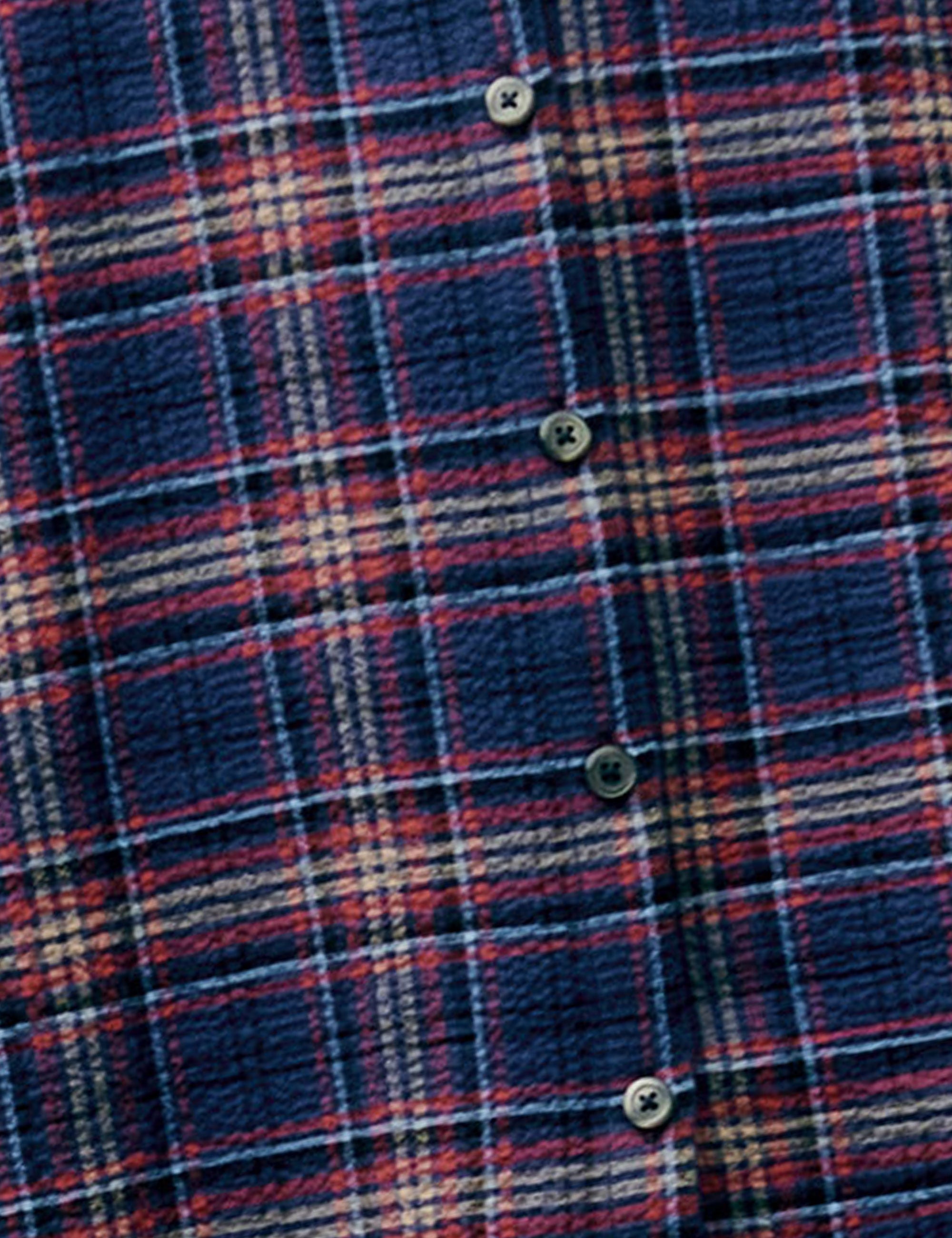 Close-up of dark plaid fabric in blue, red, and lilac tones with button detail