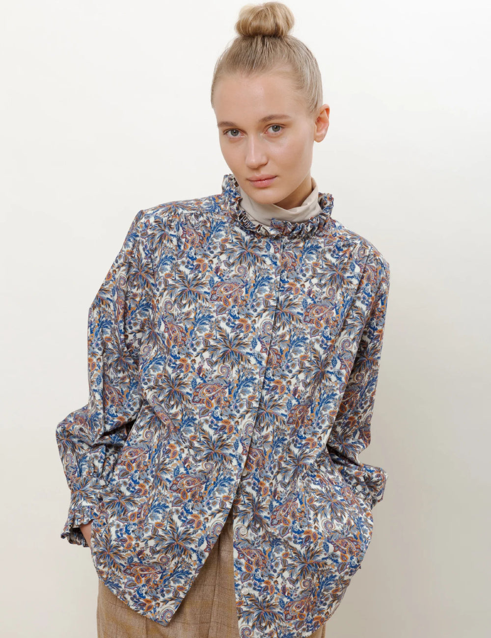 Woman in shirt jacket in red blue and grey paisley pattern with frilled stand collar