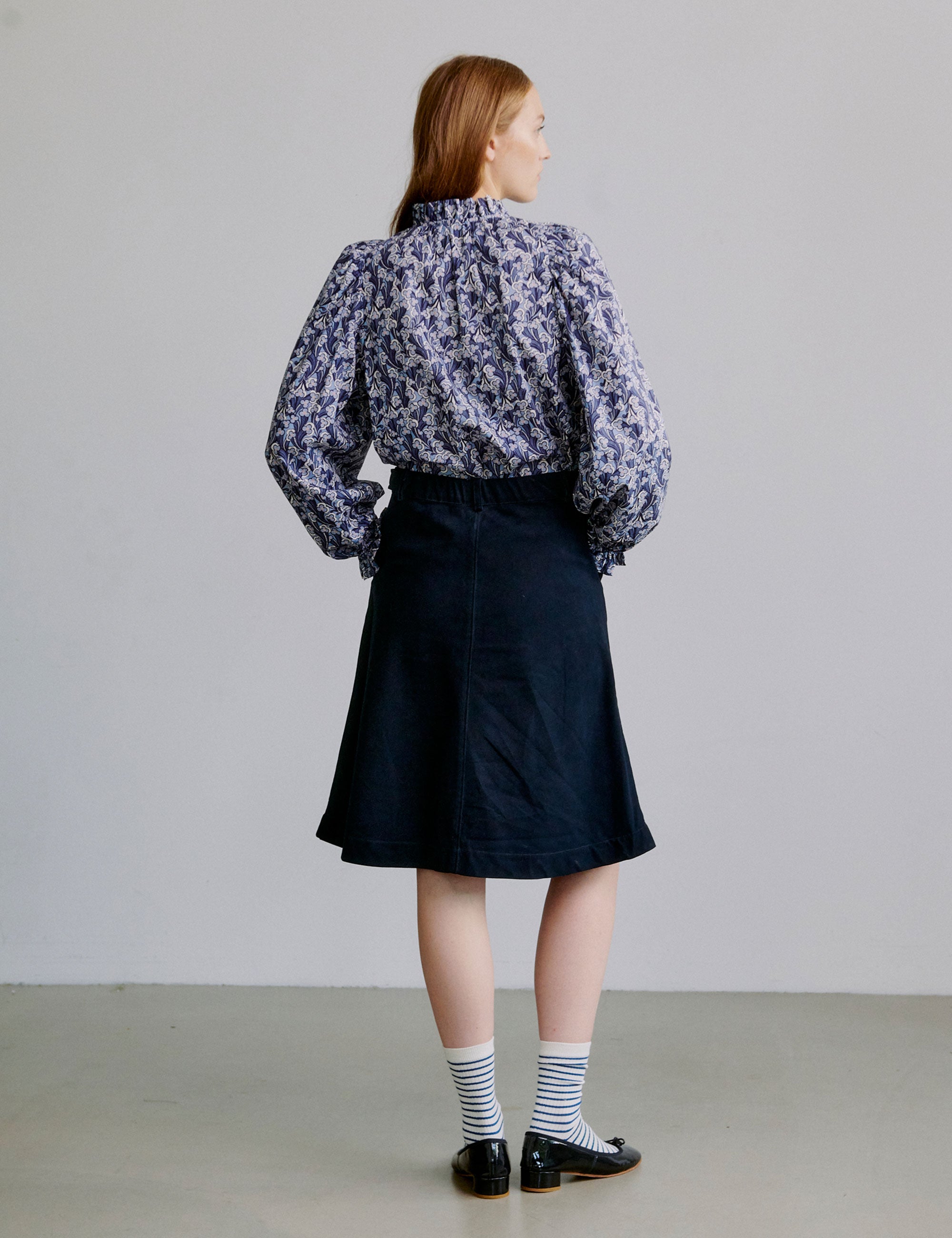 Woman wearing a blue floral blouse and blue a-line skirt