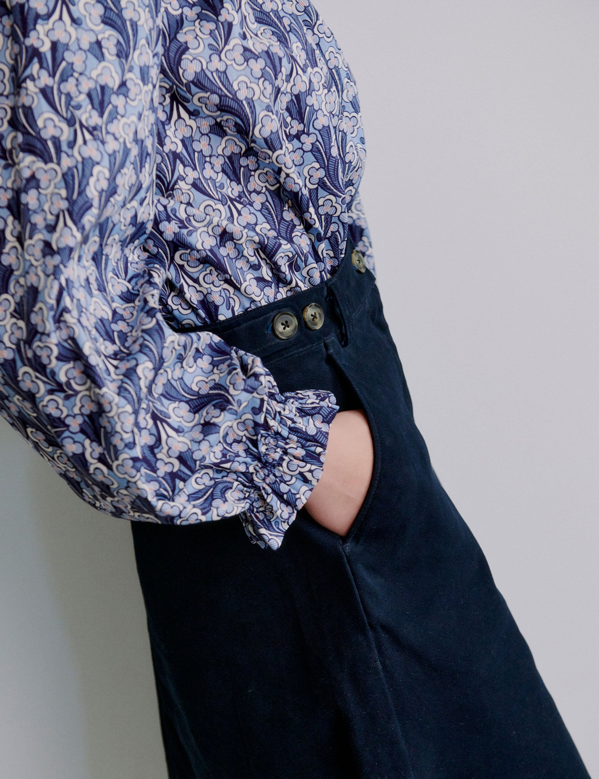 Woman wearing a blue floral blouse and blue a-line skirt with pockets and buttons