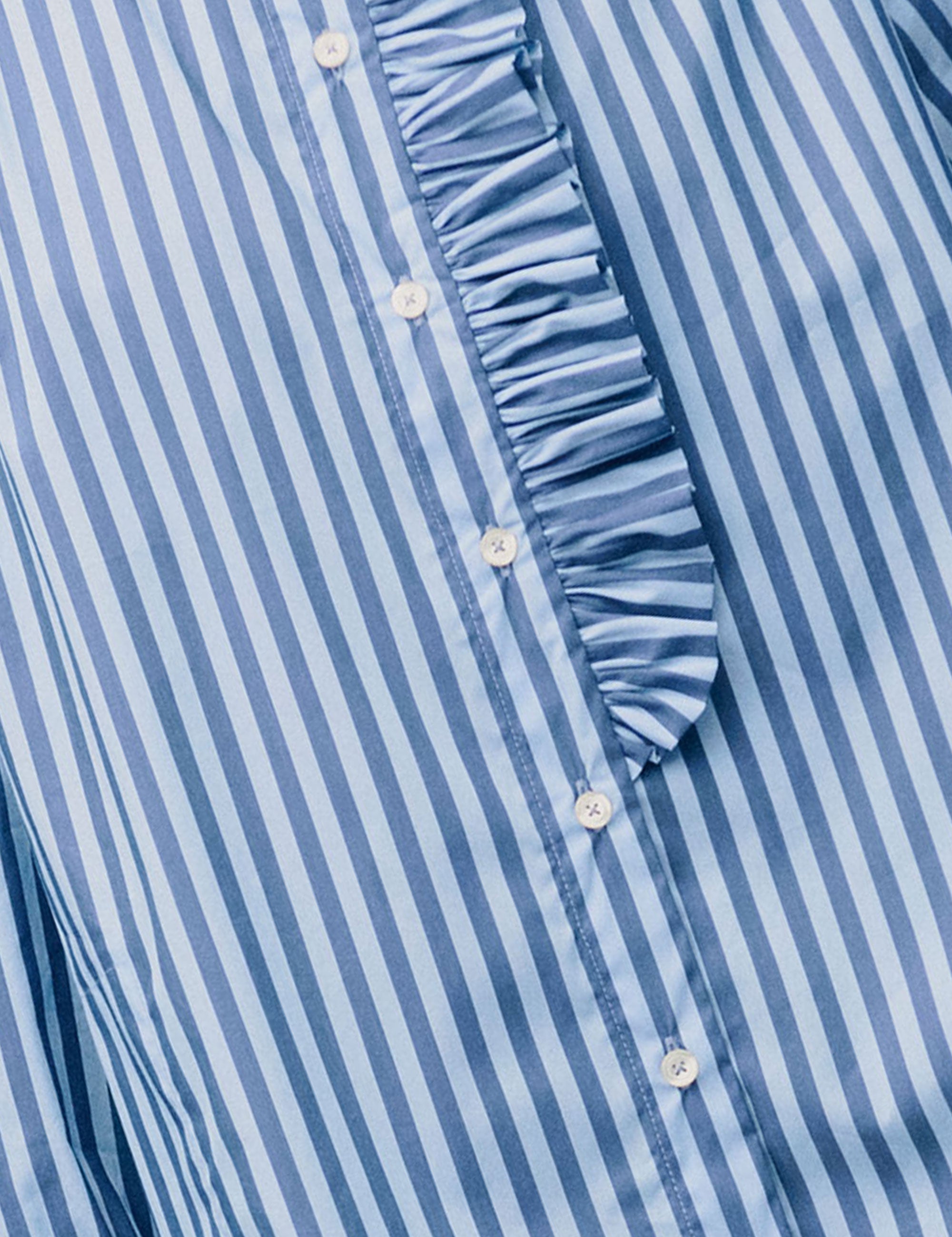 Close-up of ruffle detail and buttons on blue striped cotton shirt