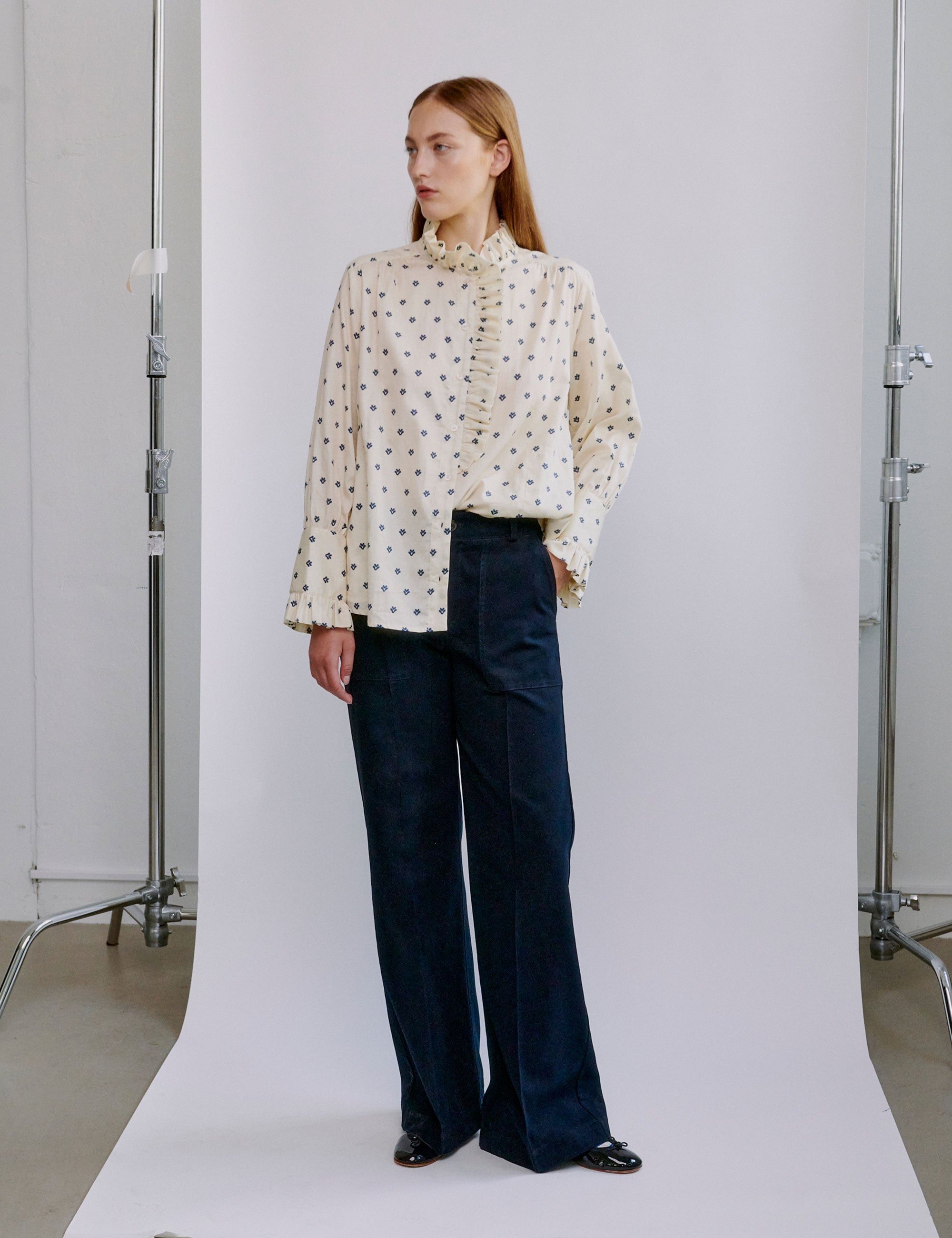 Woman wearing a polka dot blouse and dark blue wide pants 