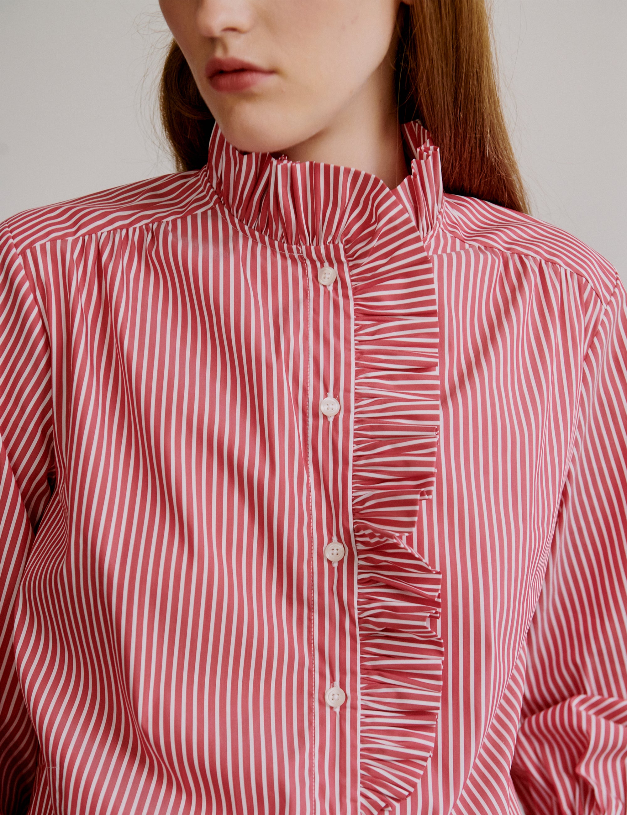 Woman in red and white striped shirt with ruffled details and buttons