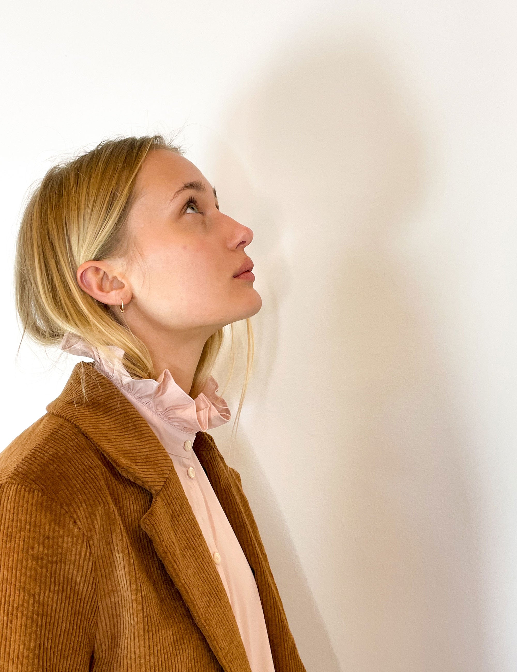 Women in pink shirt with frilled collar and brown corduroy jacket