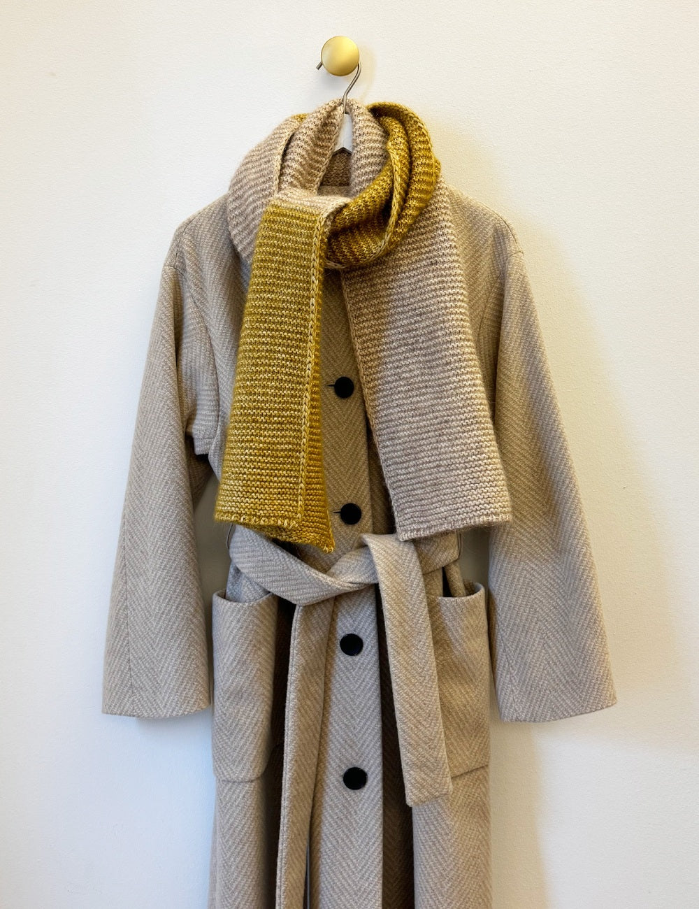 Beige long women's wool coat with belt and pockets, matched with wool scarf