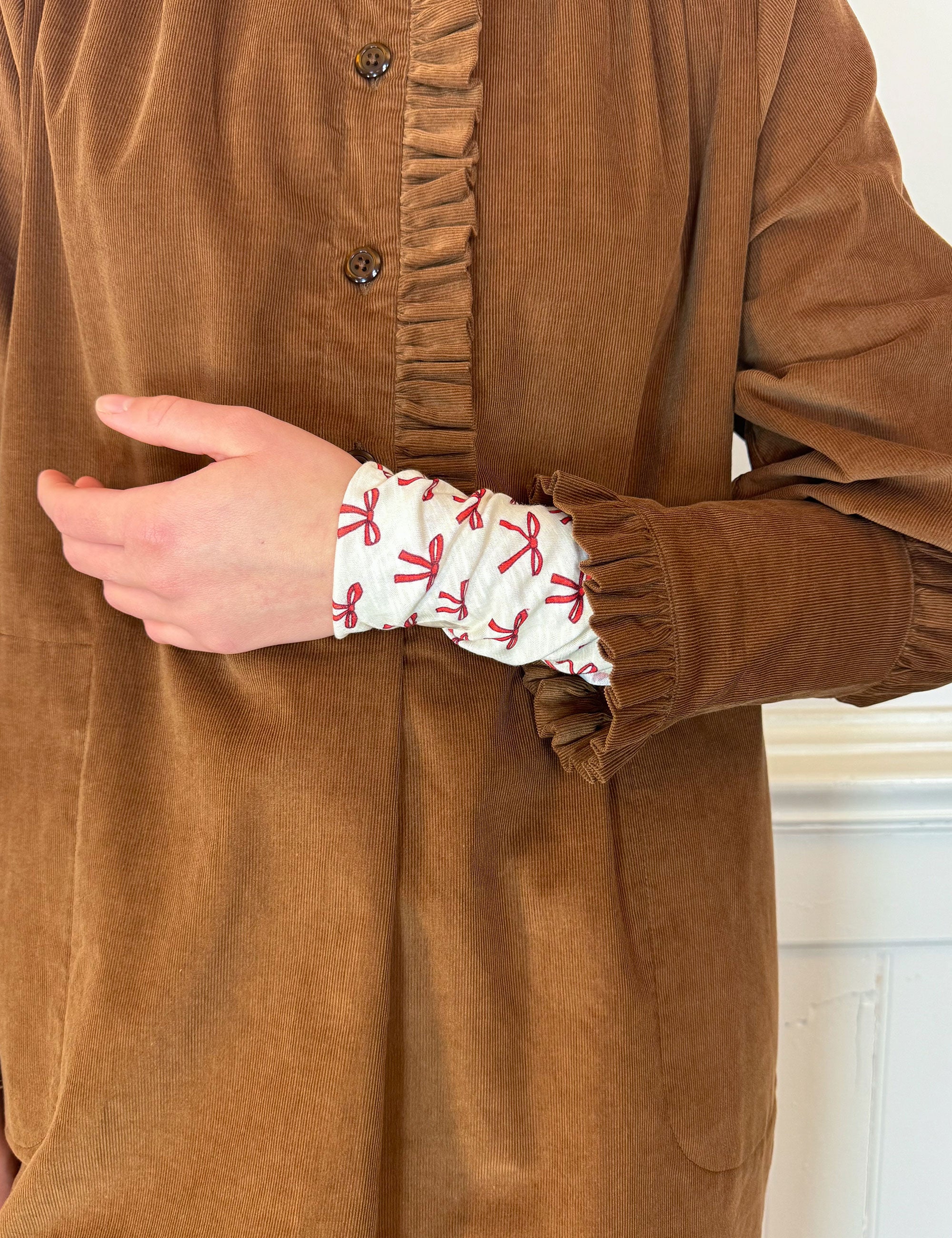 Cognac brown baby corduroy dress with buttons and frills and long sleeved t-shirt with red bow print