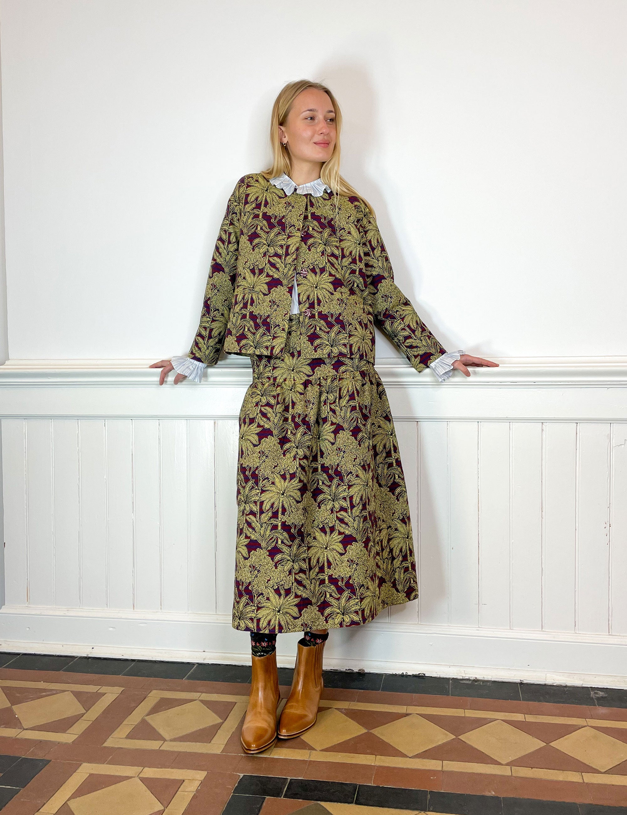 Woman in jacquard jacket and skirt with red and blue stripes and golden palm print