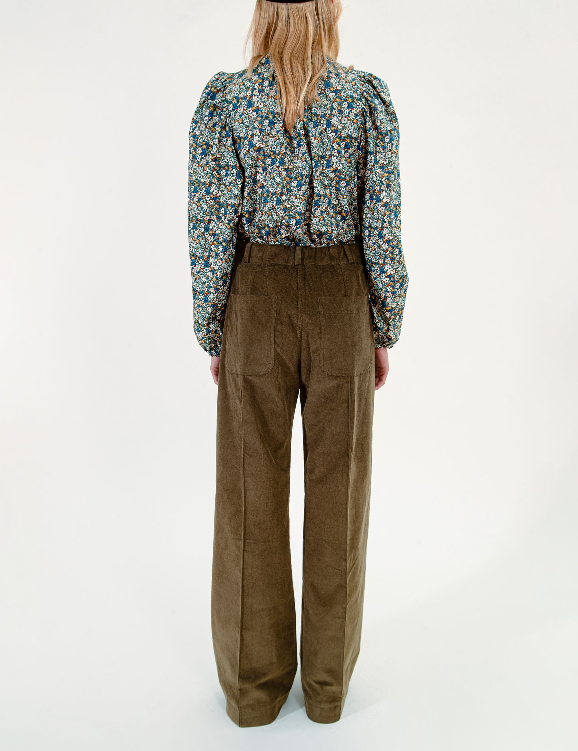 Woman wearing a floral blouse, olive green pants and a dark beret