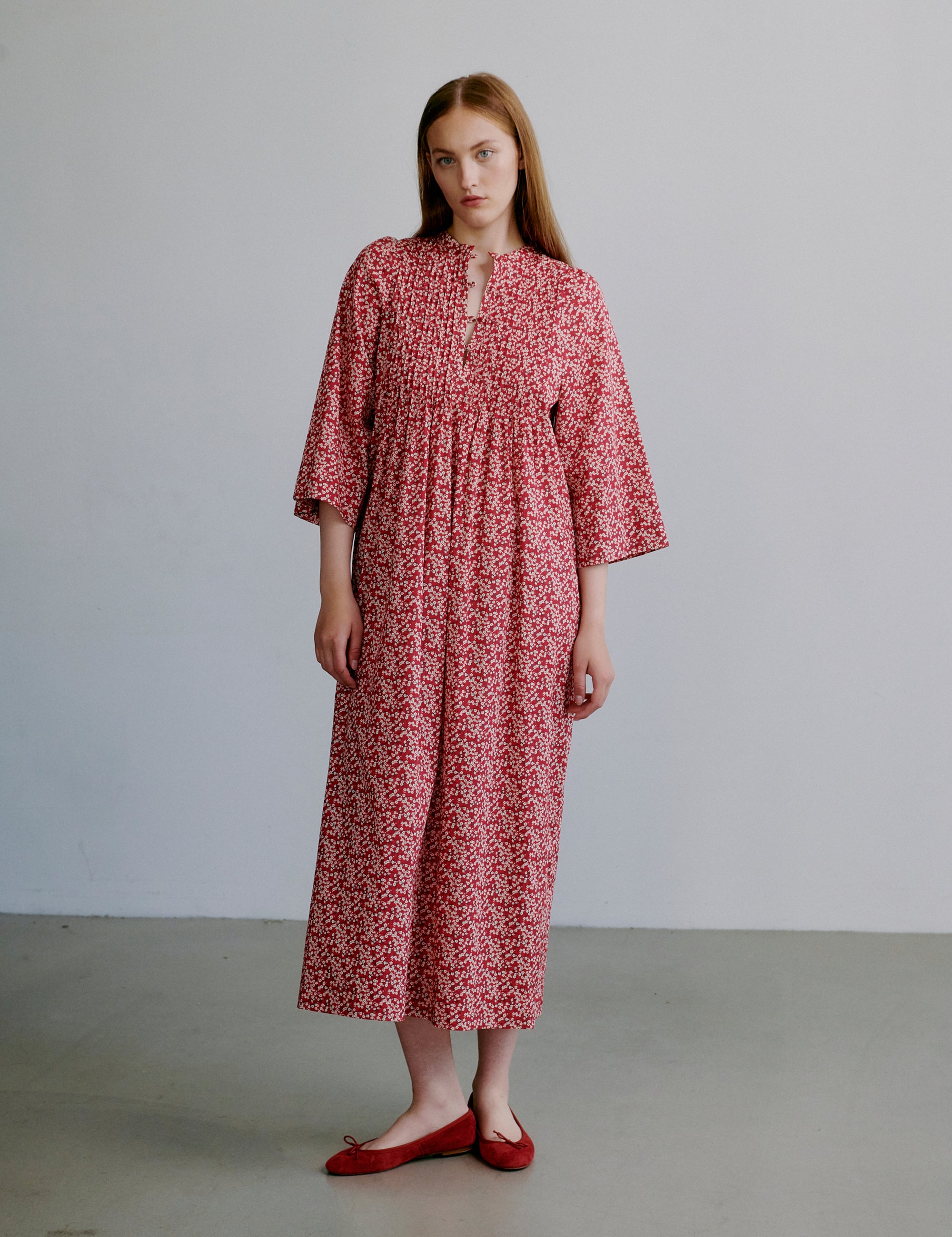 Woman wearing a red floral dress with buttons at the front and long sleeves