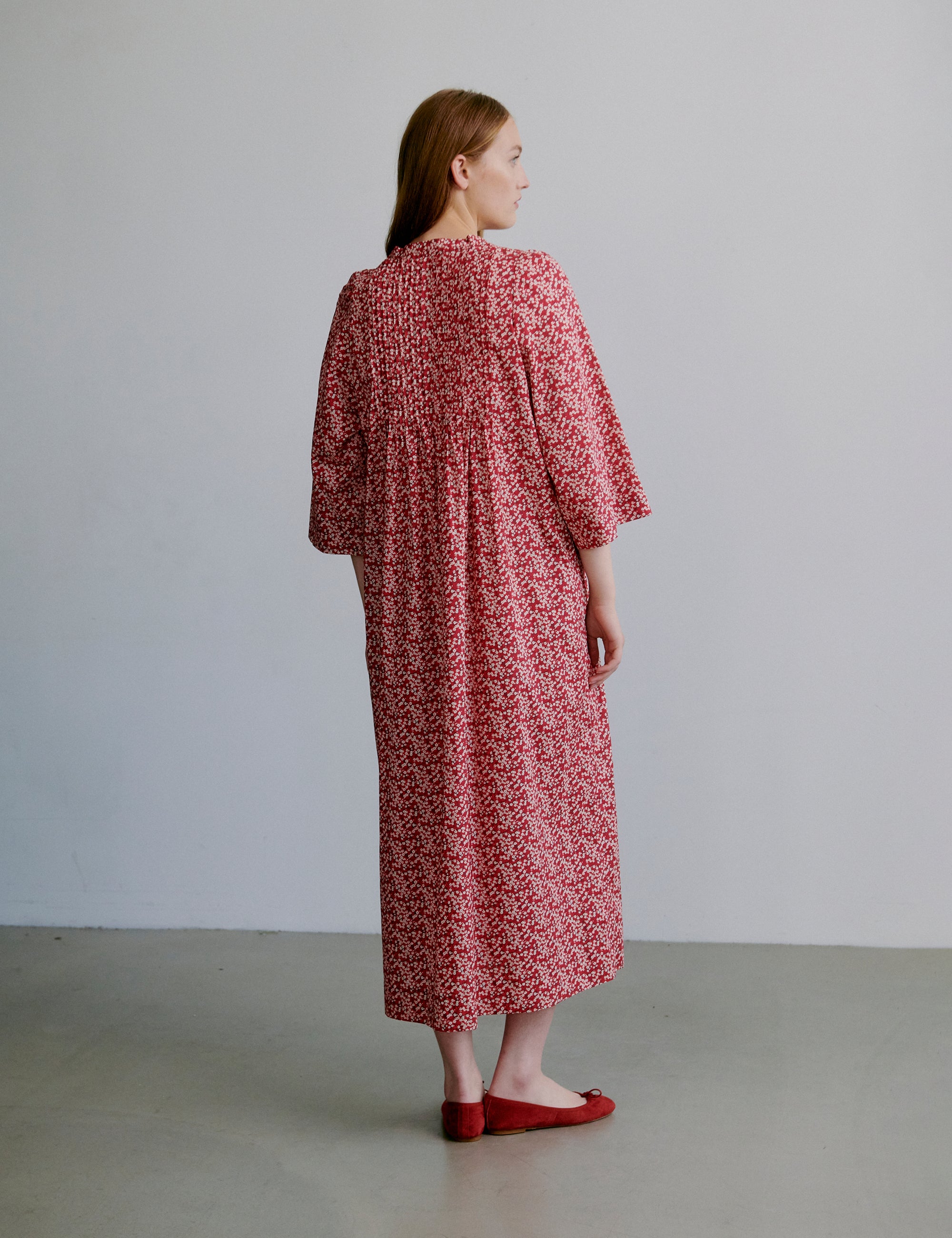 Woman wearing a red floral dress with buttons at the front and long sleeves