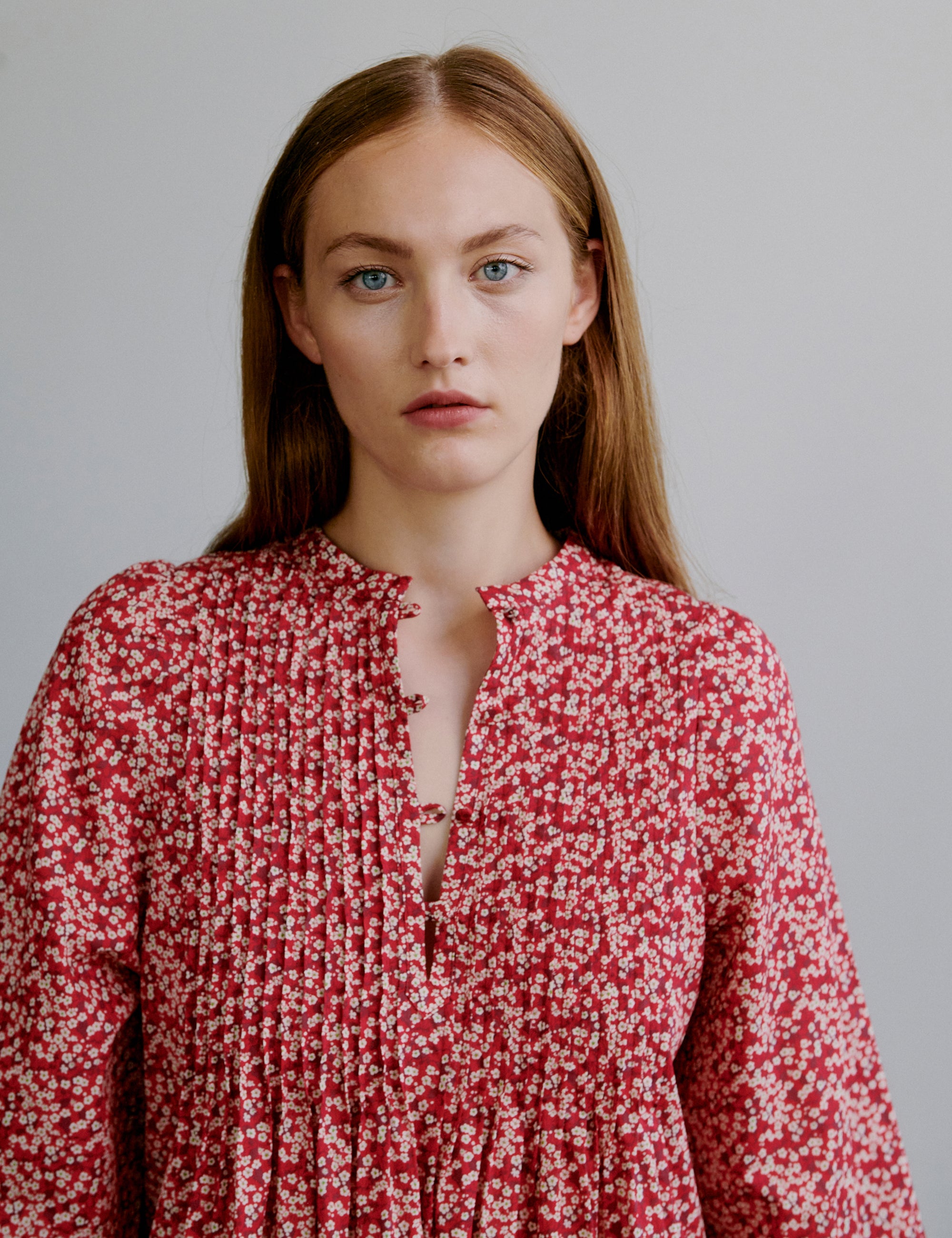 Woman wearing a red floral dress with long sleeves and buttons at the front