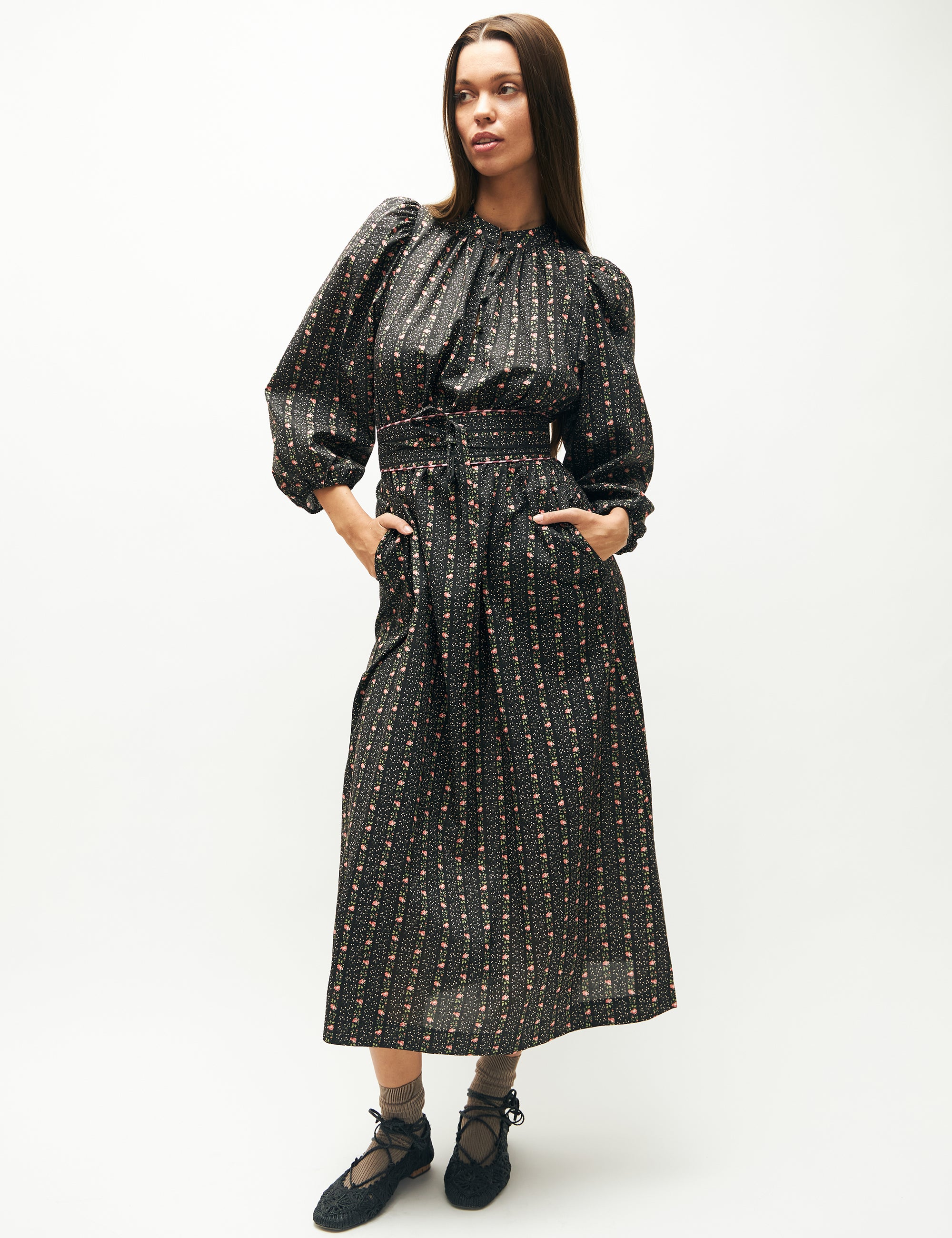 Woman in long dress with floral striped pattern, long puff sleeves and matching fabric belt
